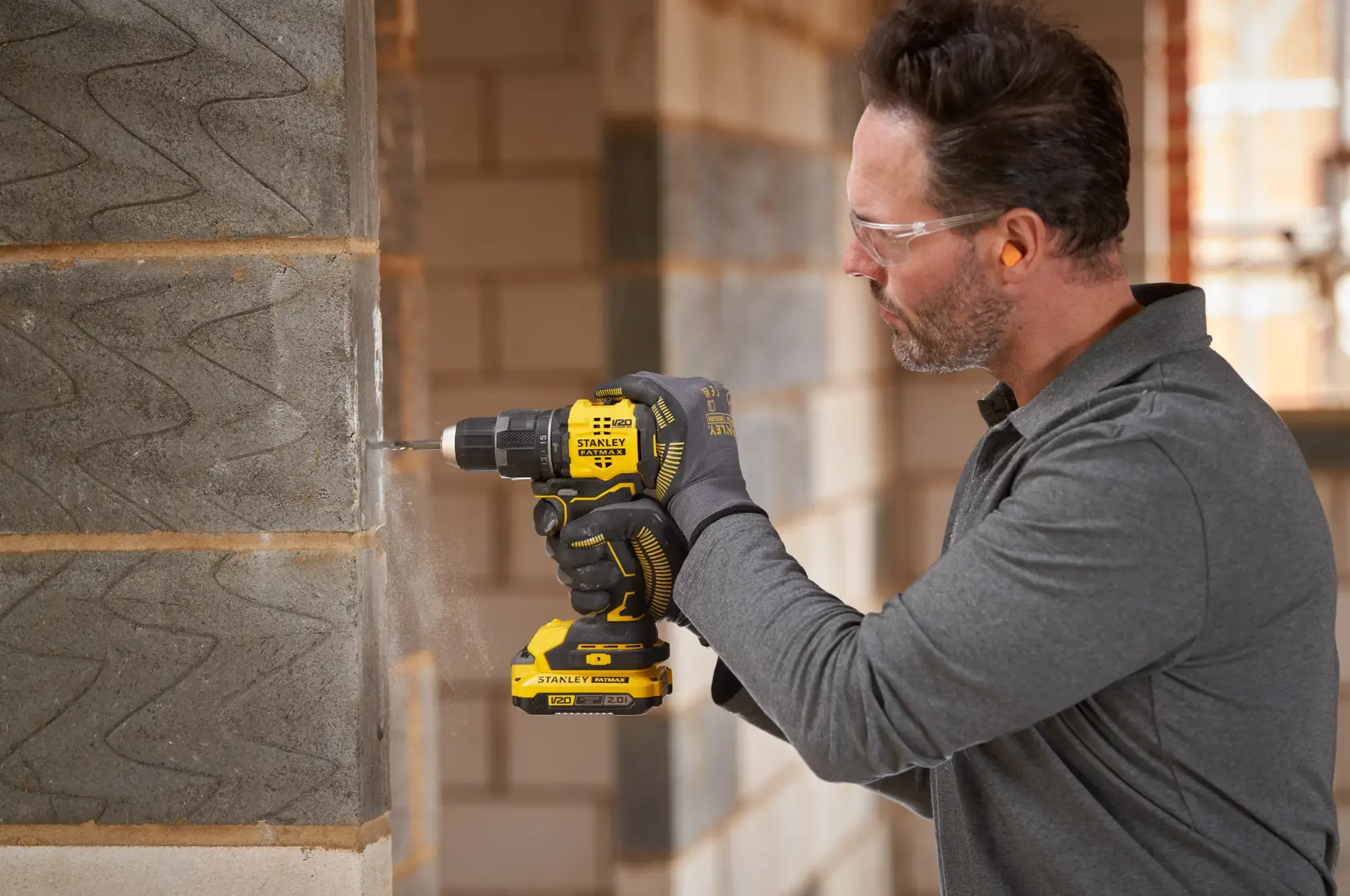 Photo of STANLEY SFMCD716B-XJ cordless drill being used to drill into a concrete wall on a construction site.