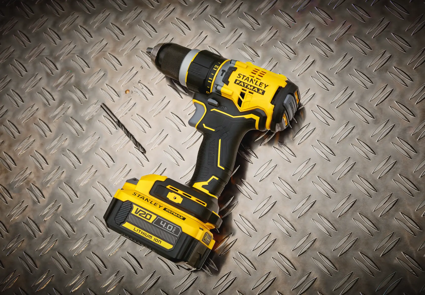 STANLEY SFMCD721M2K cordless drill with V20 battery on diamond plate surface, product photography.