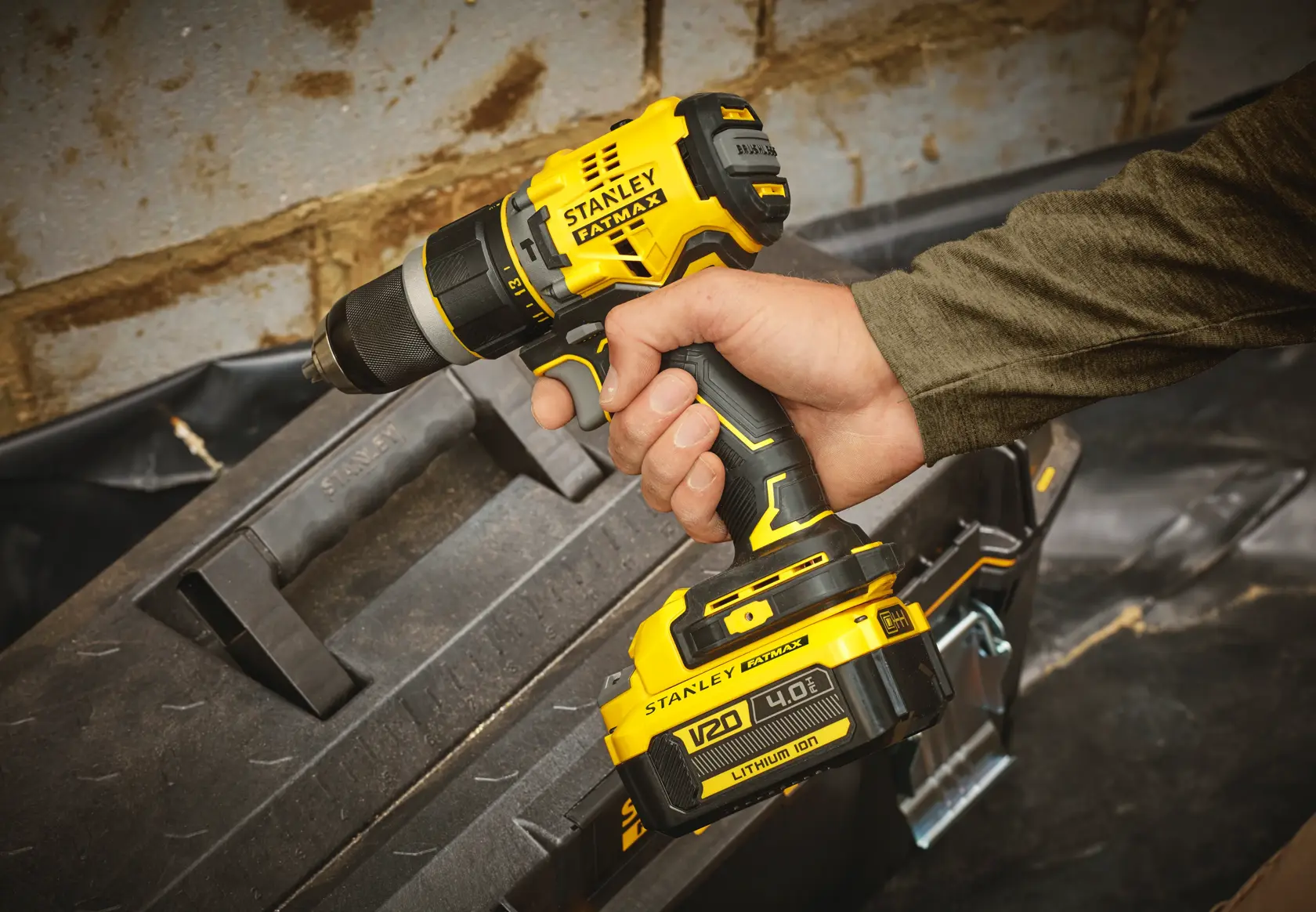 Stanley SFMCD721M2K cordless drill with V20 4.0Ah battery held in hand, photographed on construction site.