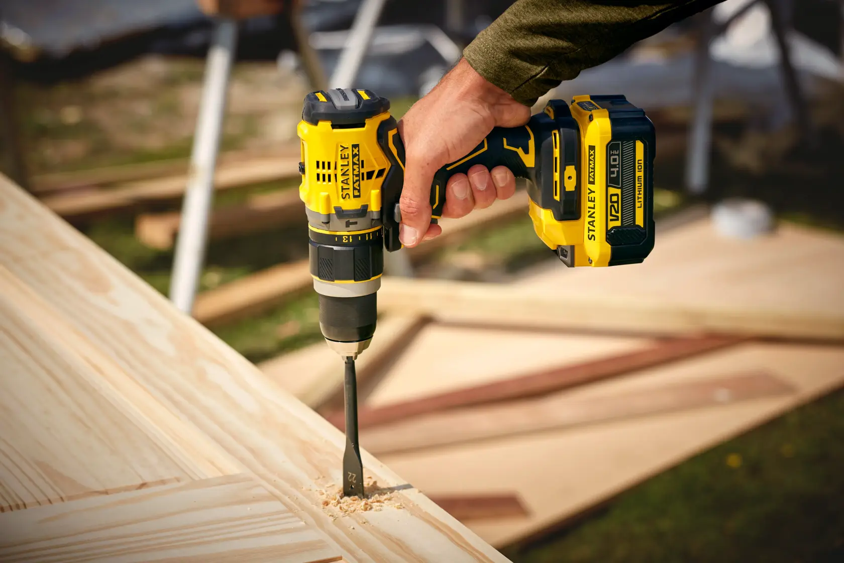 STANLEY SFMCD721M2K cordless drill in use, drilling into light wood outdoors, close-up view.