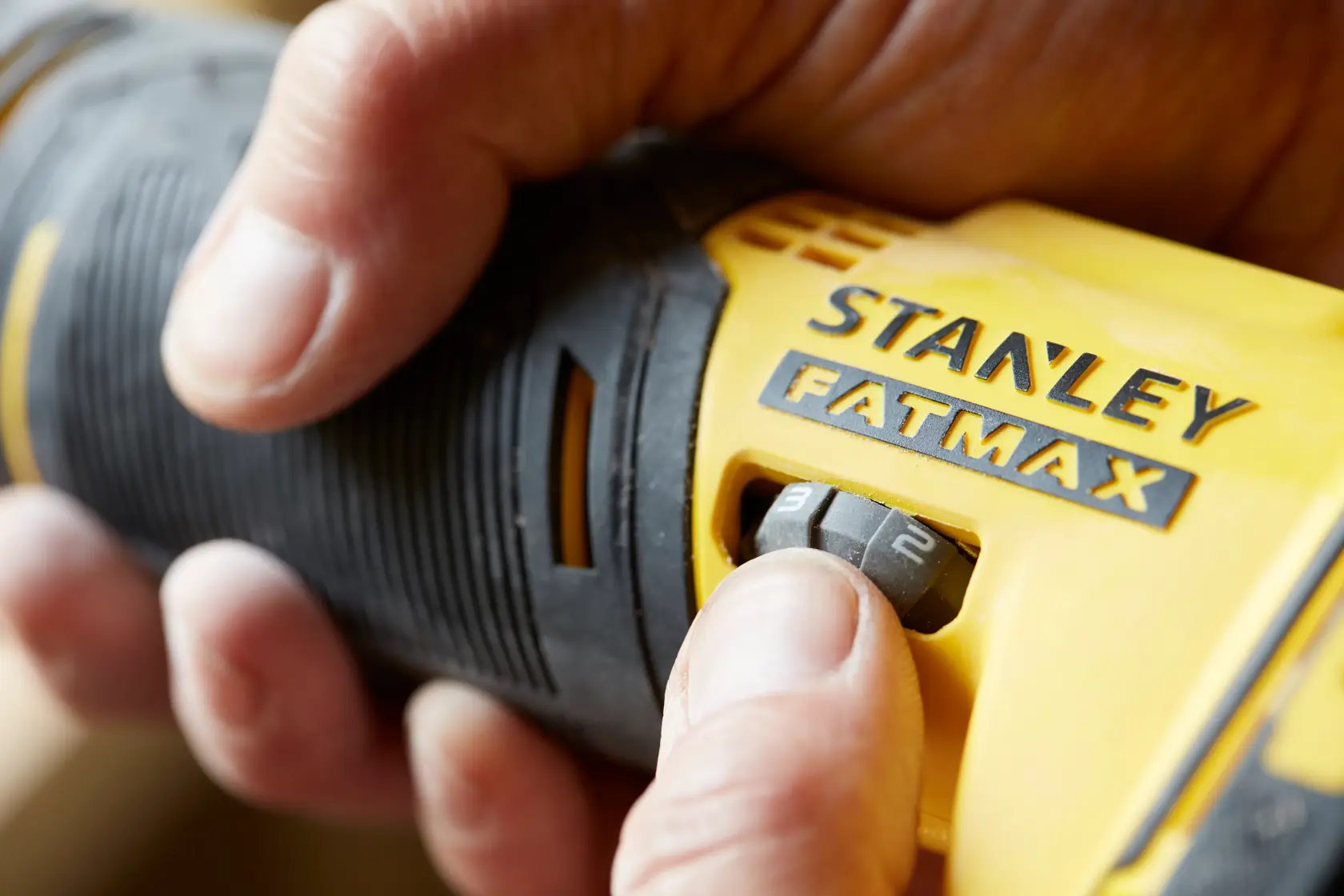 Nahaufnahme des STANLEY SFMCE500B FATMAX Werkzeugs mit Hand am Geschwindigkeitsregler, Produktfotografie.