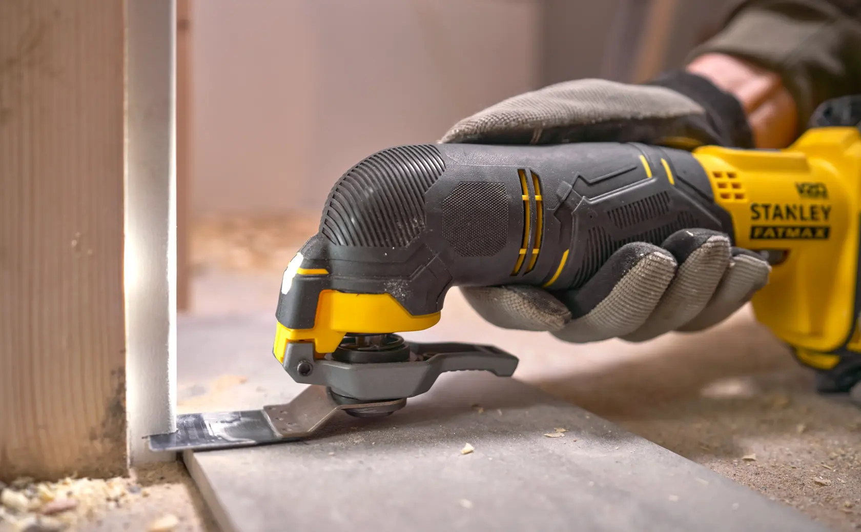 Stanley SFMCE500D1K oscillating multi-tool in use, close-up, cutting wood flooring, photo of product action.