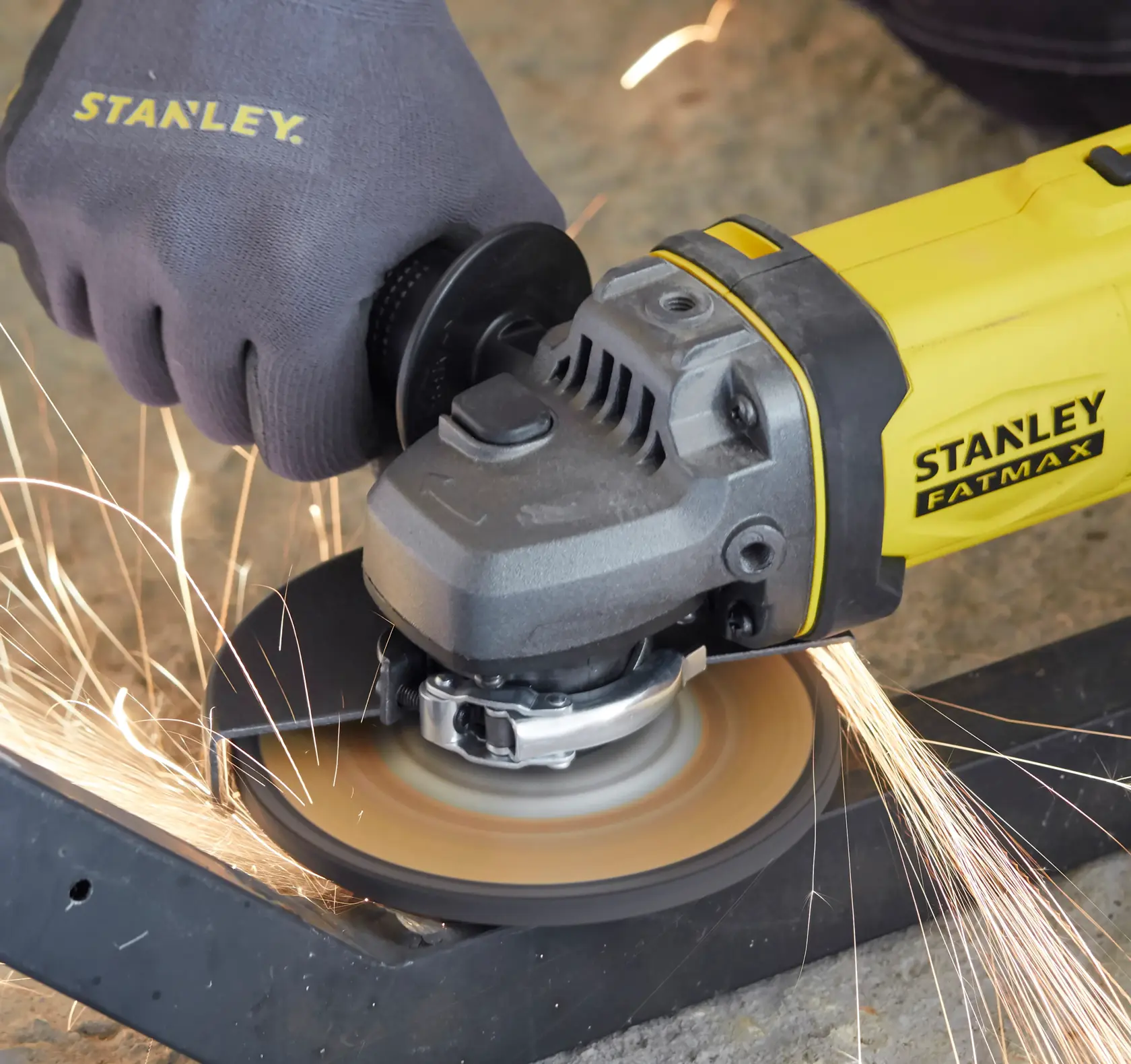 STANLEY SFMCG400M2K angle grinder in use, grinding metal with sparks, close-up view.