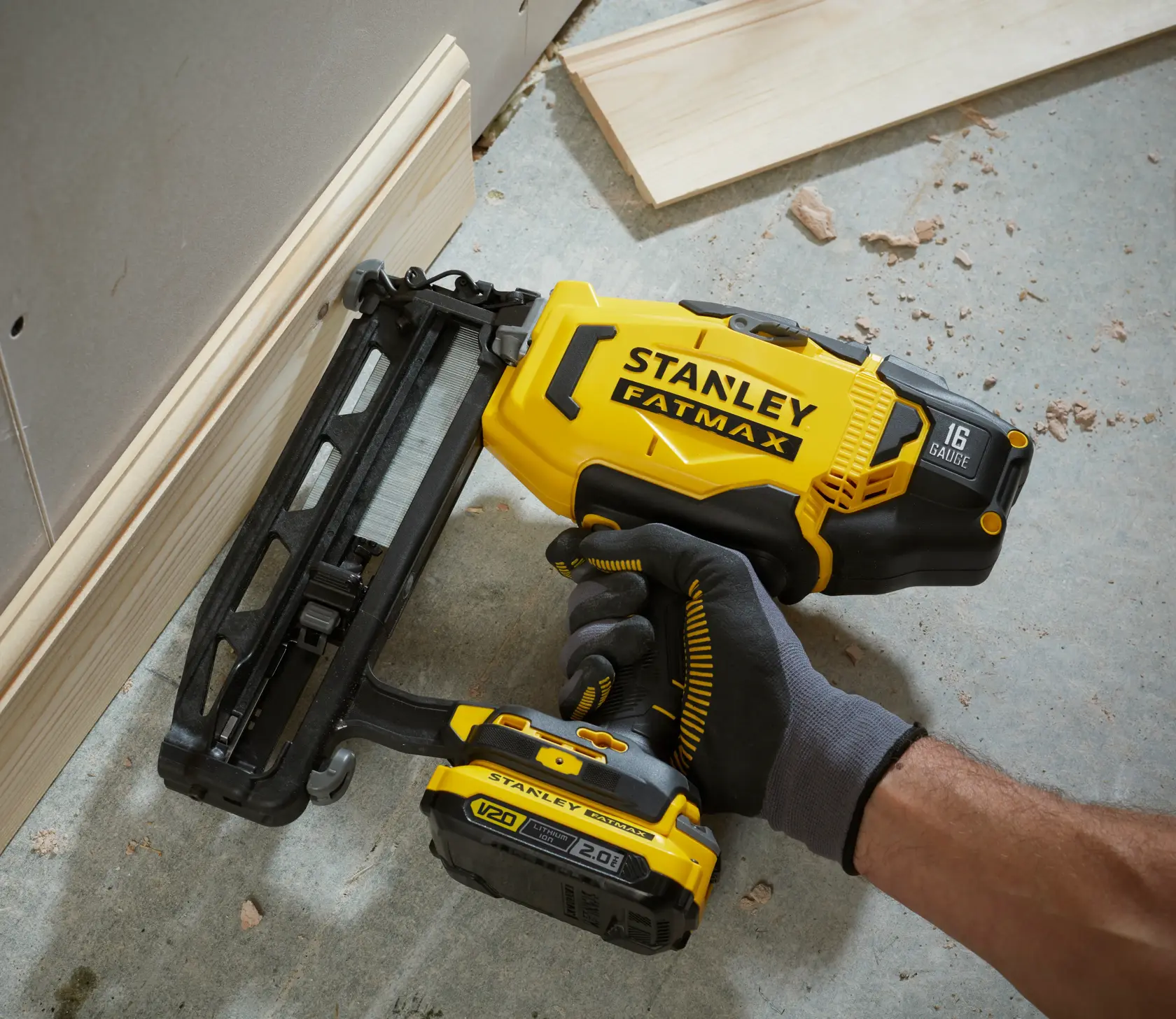 STANLEY SFMCN616D2K nail gun, yellow and black, used for wood baseboard installation, close-up.