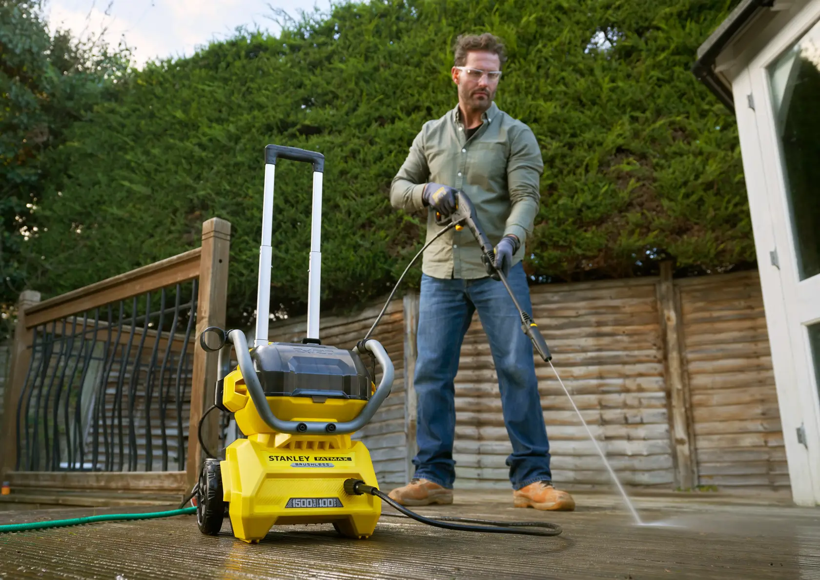 STANLEY SFMCPW1500B pressure washer on patio, shown in use by person cleaning wooden deck outdoors.