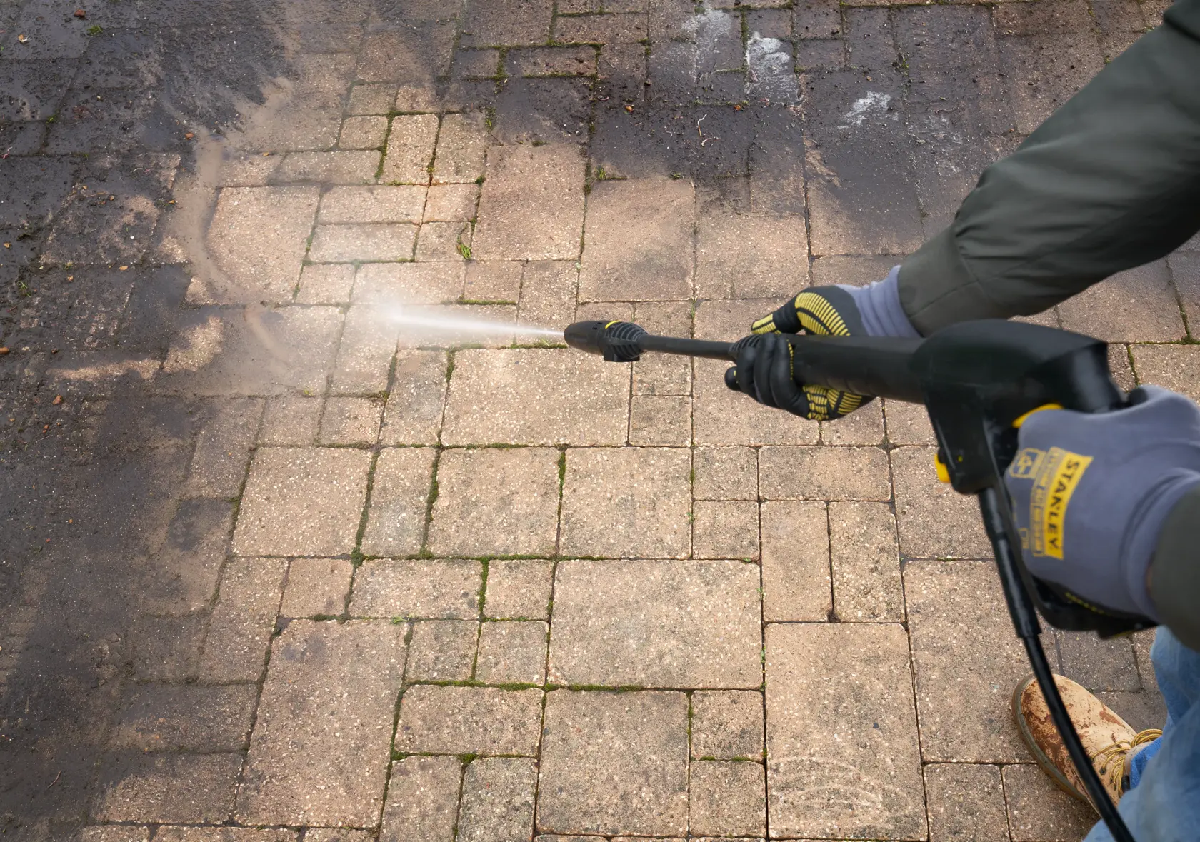 Stanley SFMCPW1500B pressure washer cleaning dirty stone patio, close-up angle.