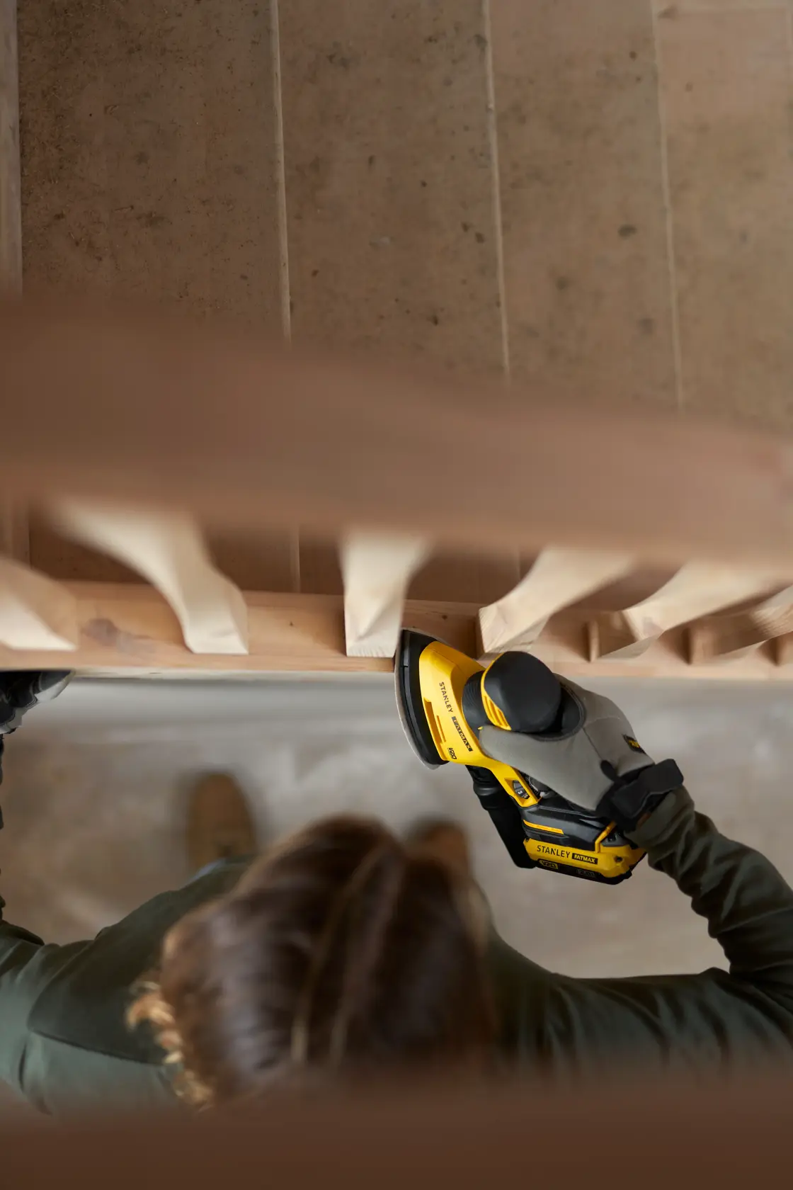 STANLEY SFMCW221B Schleifer im Einsatz an Holztreppe, Nahaufnahme, Bediener mit Handschuhen.
