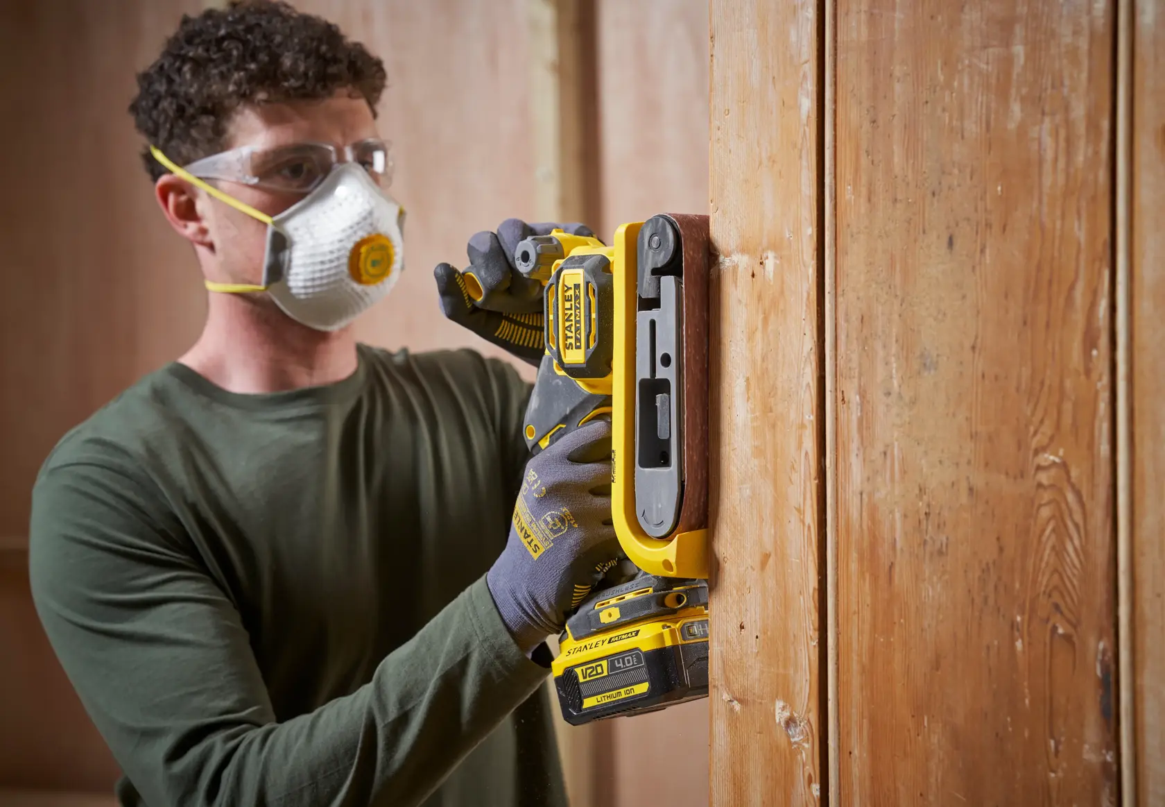 STANLEY SFMCW223B-XJ cordless sander in use on vertical wood surface, close-up photography.