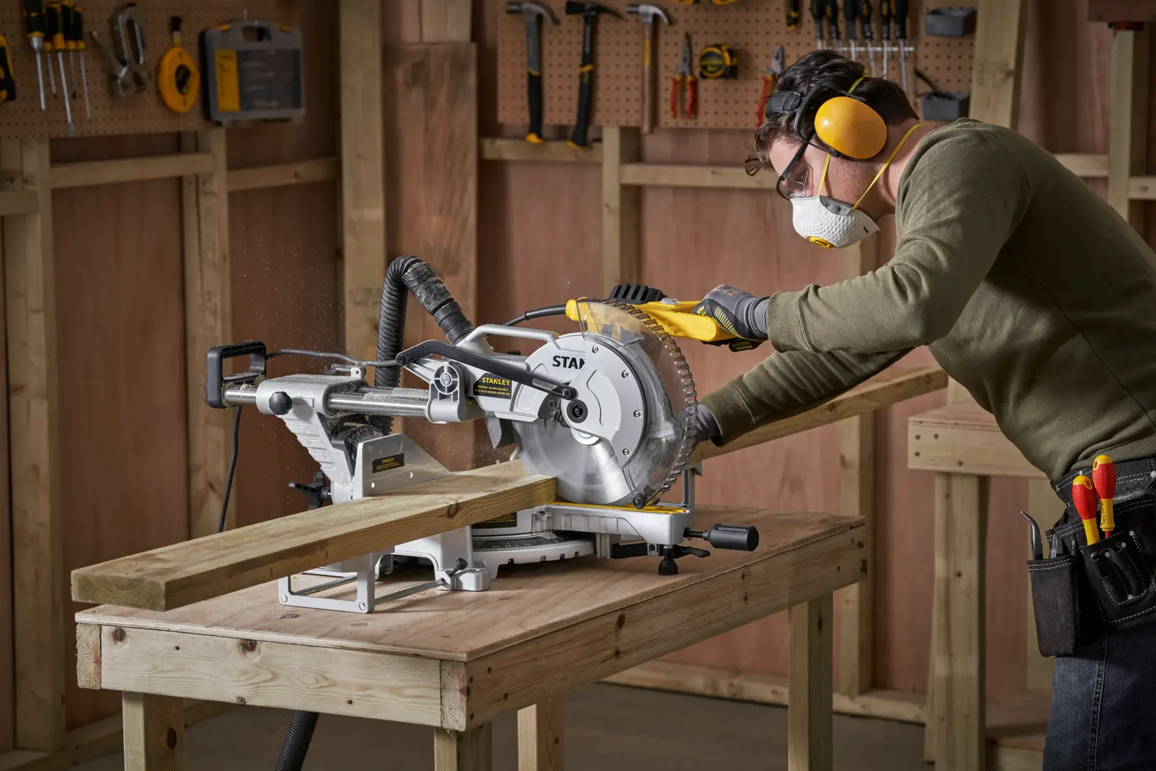 STANLEY SM1800 sliding mitre saw on workbench, used to cut wood in a workshop setting.