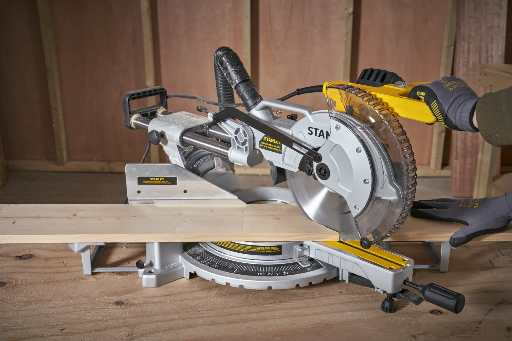 Photo of STANLEY SM1800 miter saw cutting wood, close-up view in workshop setting.
