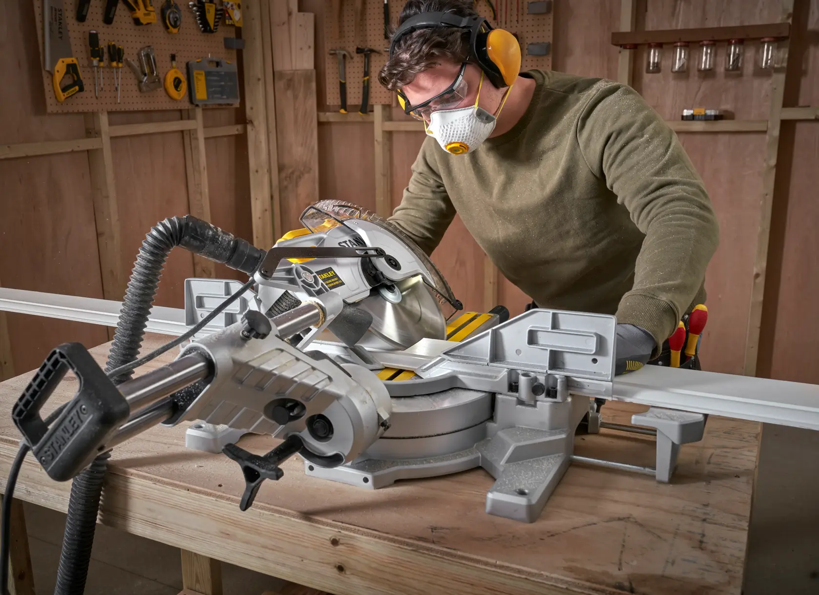 STANLEY SM1800 sliding compound miter saw in use on wooden workbench in workshop setting.