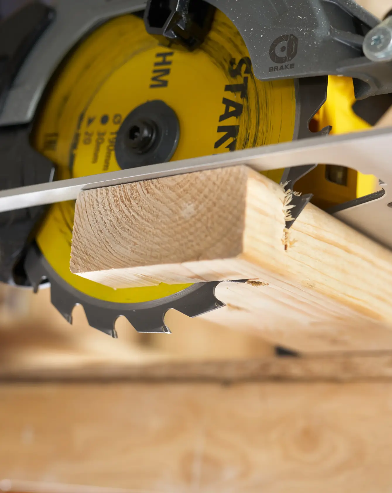 Photo of STANLEY STA13030 circular saw cutting wood plank, close-up on yellow blade and clean cut.