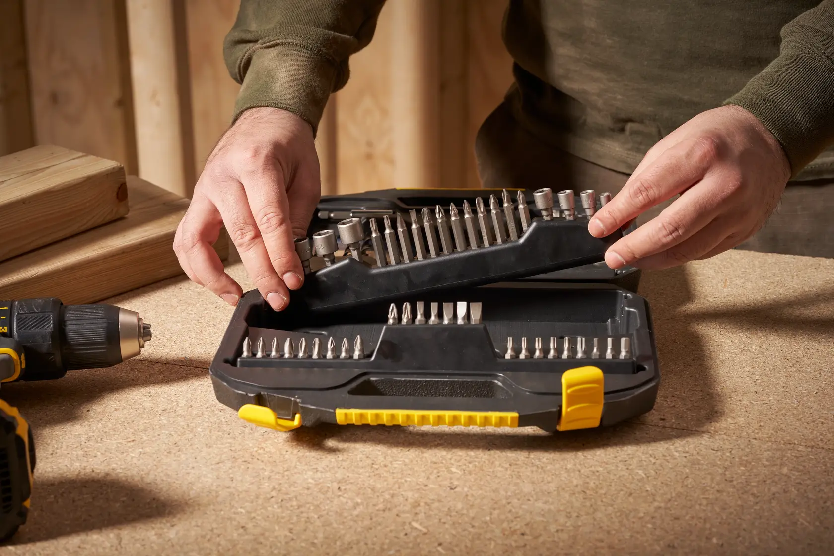 STANLEY STA7184 screwdriver bit set case being opened on a workbench, with drill and wood in background.