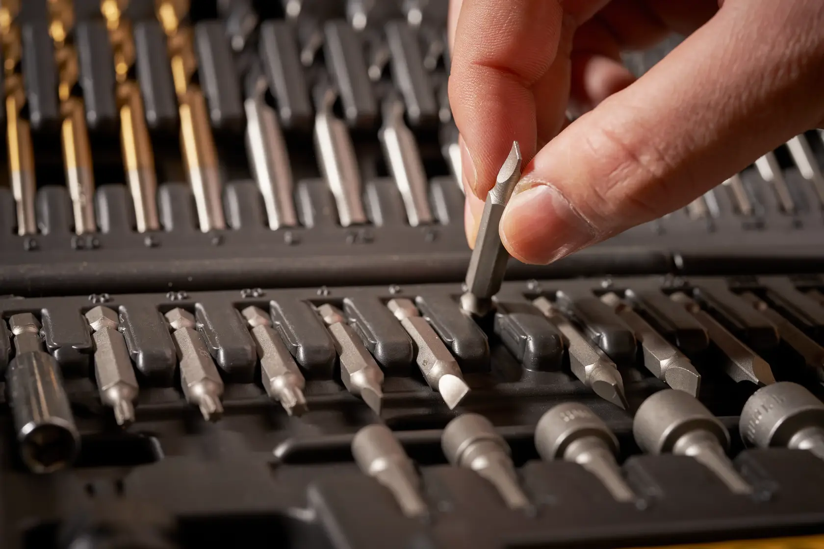 STANLEY STA88548 hand selecting screwdriver bit from assorted bit set in case, close-up photo.