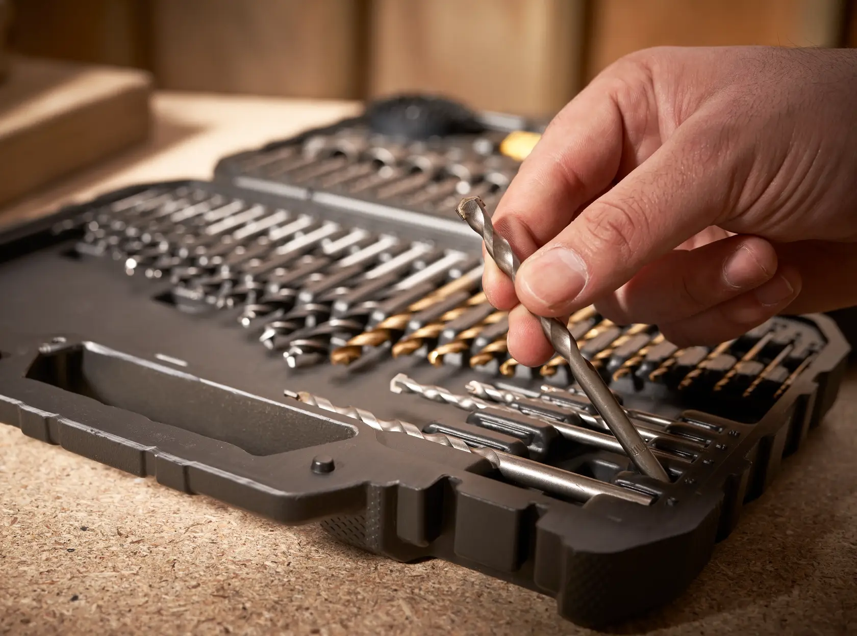 STANLEY STA88548 drill bit set case with hand selecting a bit, close-up angle on workbench.