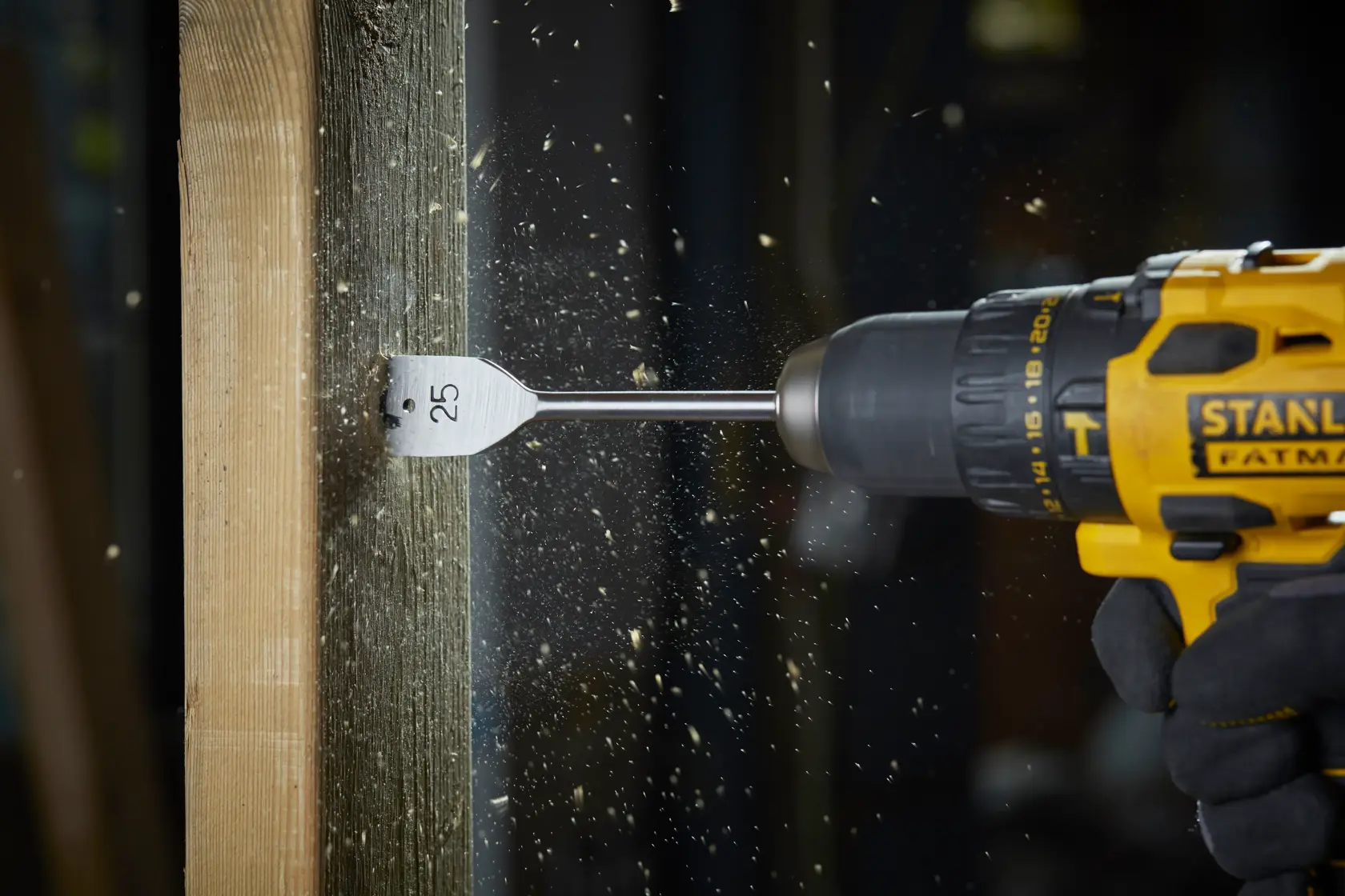 STANLEY STA88556 flat wood drill bit in action, drilling wood with shavings flying, side view, product photography