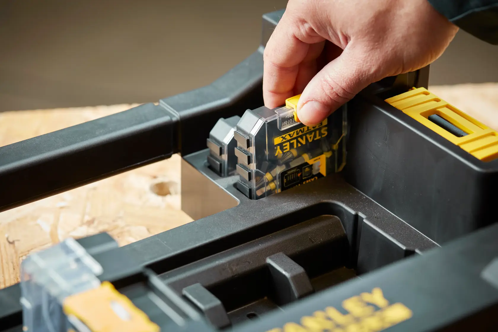 STANLEY STA88580 digital measuring tool held in hand, shown inserted in black and yellow storage case, close-up.