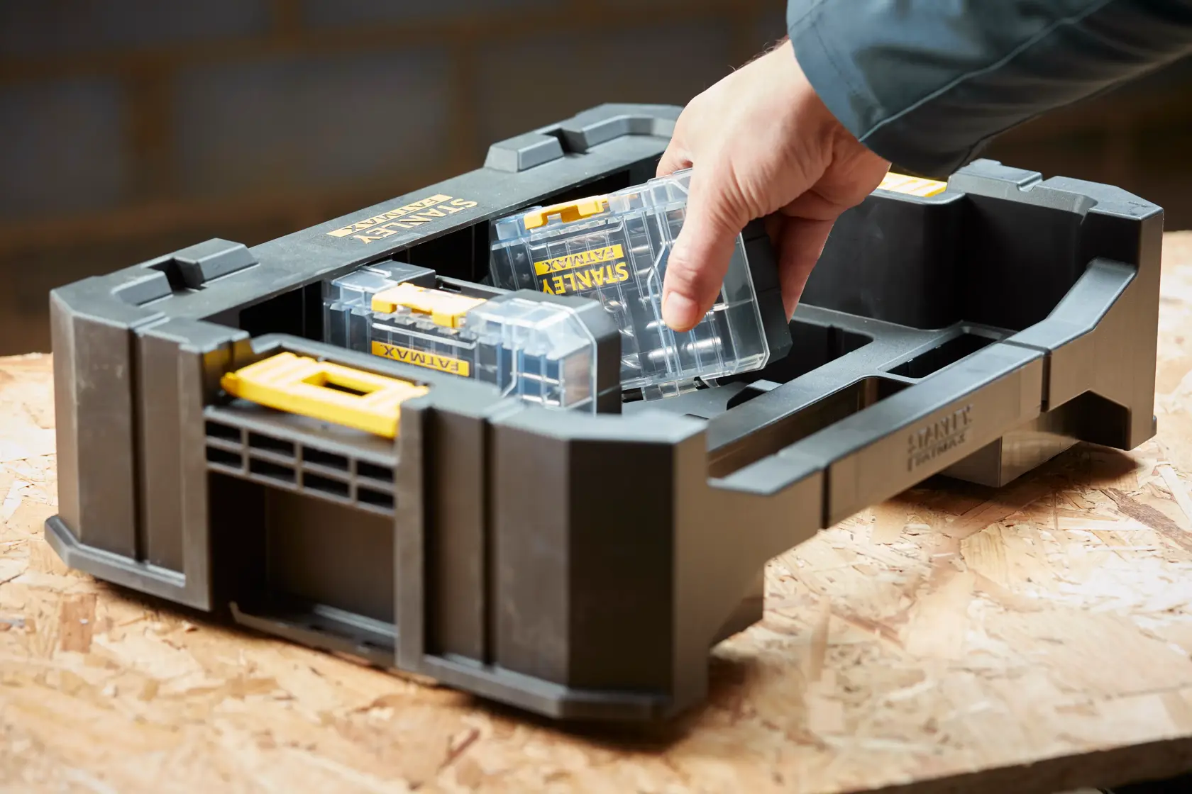 STANLEY STA88580 organizer tray with removable clear plastic cases, shown on a workbench, hand taking one case.