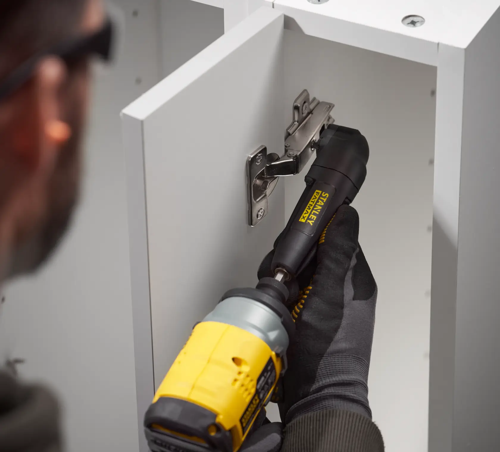STANLEY STA88582-XJ right angle drill attachment used on cabinet hinge, close-up photography.