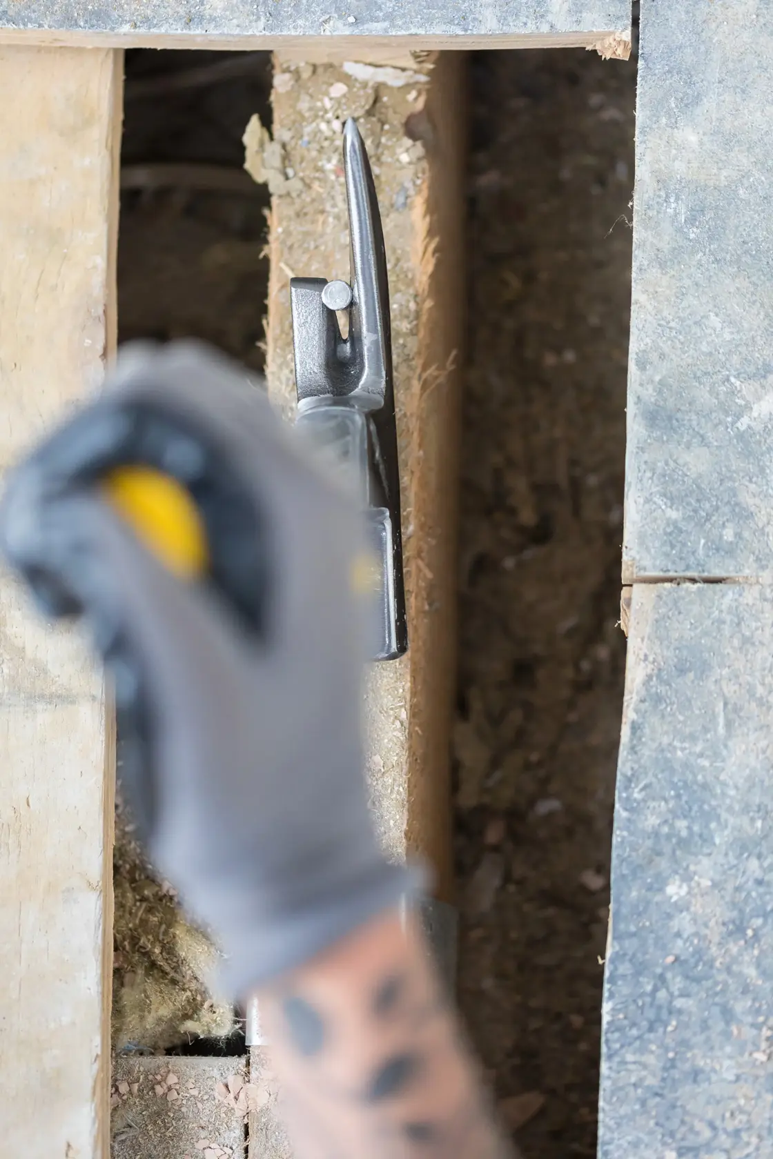 STANLEY STHT0-51312 claw hammer in use on wood during construction, partial view with gloved hand.