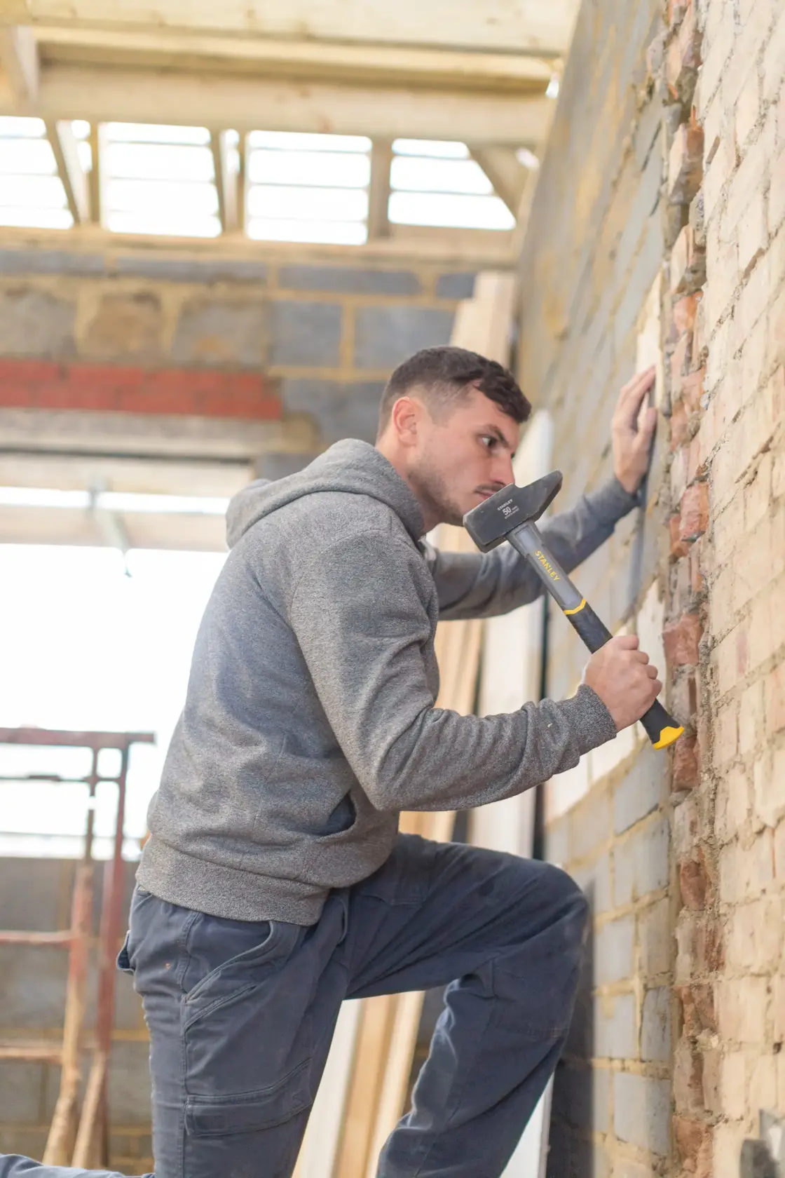 Photo of person using STANLEY STHT0-54157 sledge hammer on brick wall at a construction site.
