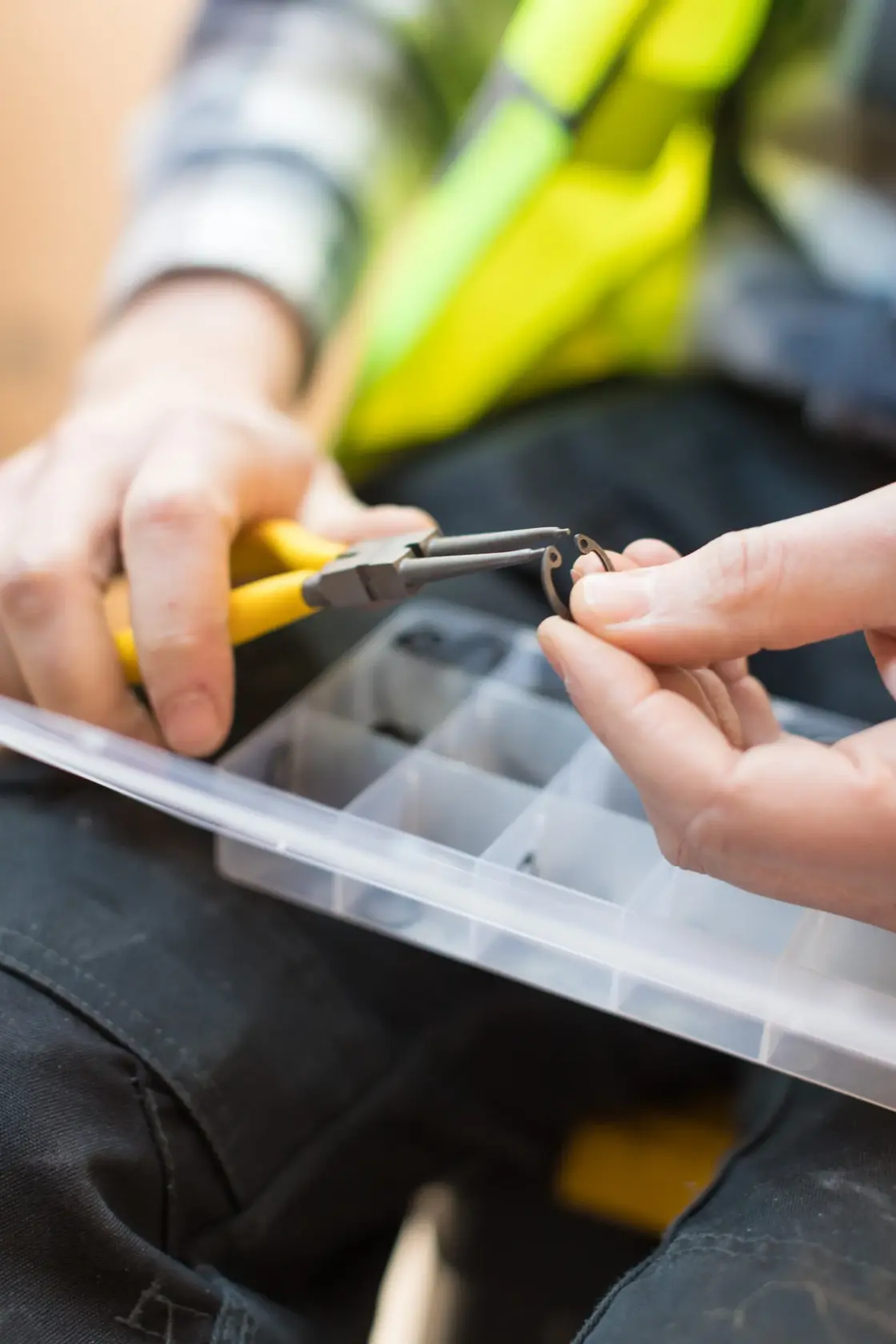 STANLEY STHT0-75412 photography of yellow-handled pliers holding a small ring above a plastic organizer box.