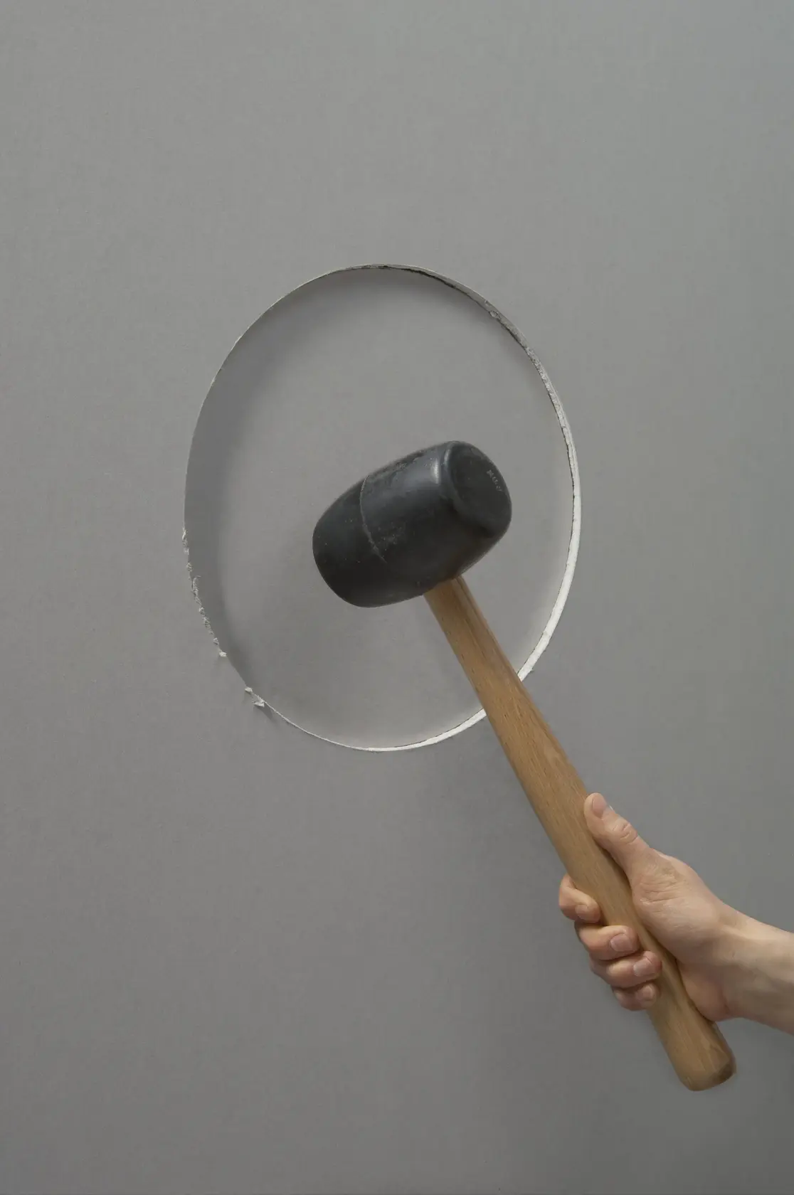 STANLEY STHT1-05878 Gummihammer mit Holzgriff, Seitenansicht, gegen graue Wand mit kreisförmigem Ausschnitt gehalten.