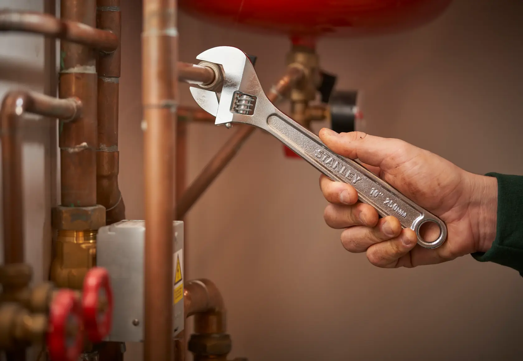 STANLEY STHT13121-0 adjustable wrench used on copper pipes, product held in hand.
