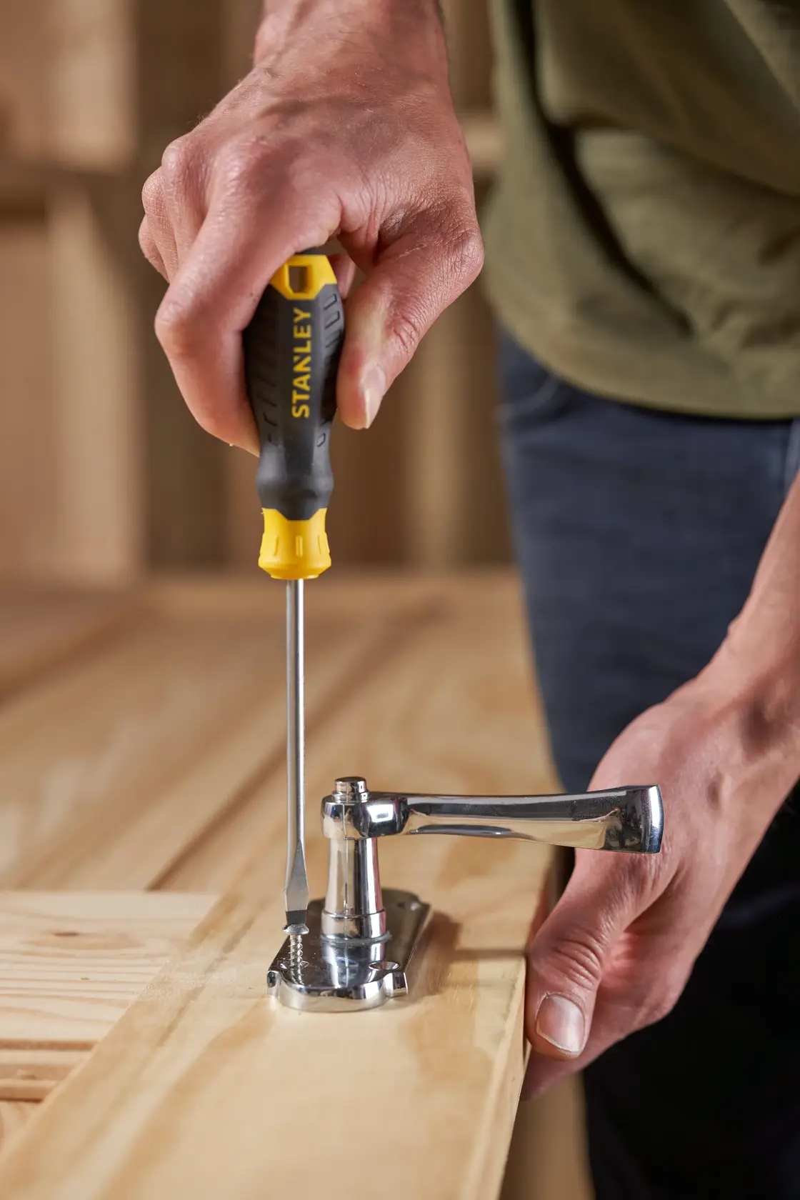 Photo of STANLEY STHT16146-0 screwdriver adjusting metal hinge on wooden surface.