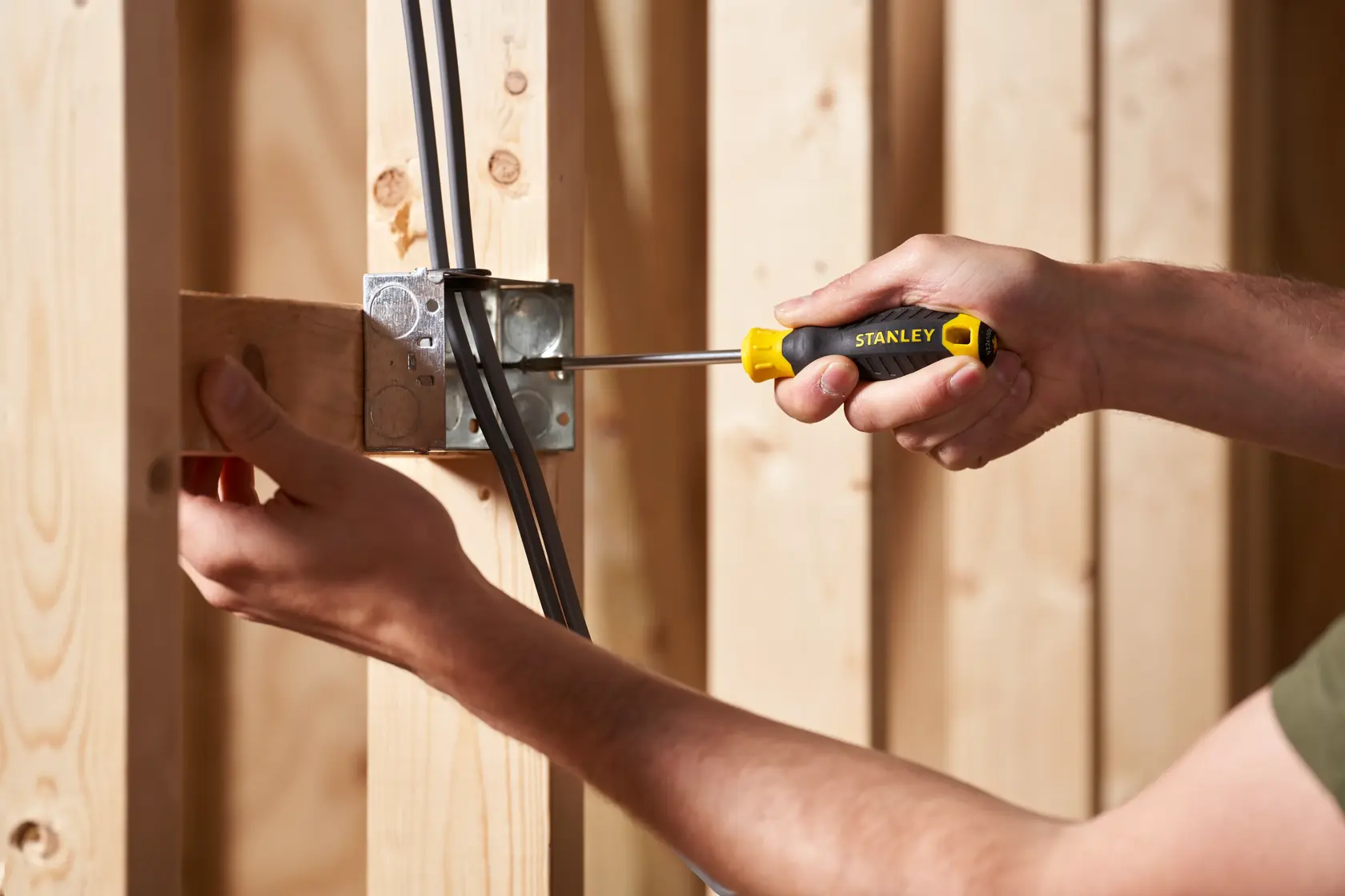 STANLEY STHT16163-0 screwdriver used to install wiring in a metal electrical box, close-up in construction setting.