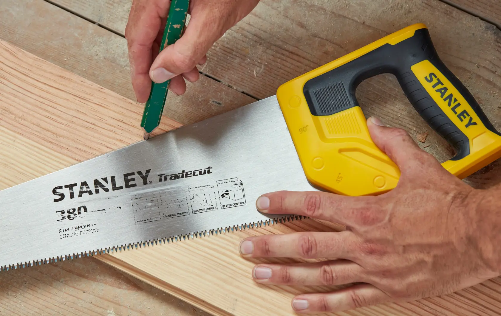 STANLEY STHT20348-1 hand saw with yellow handle on wood, close-up showing cutting teeth and brand details.