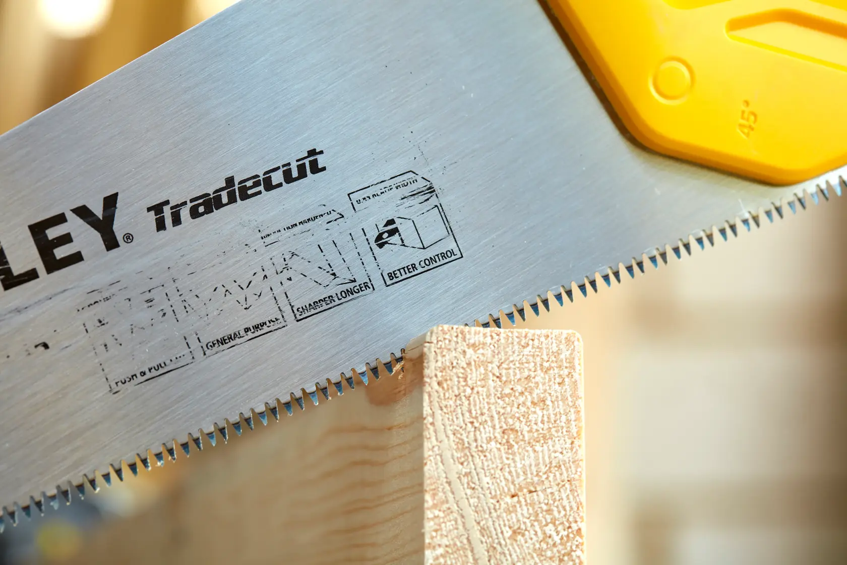 STANLEY STHT20348-1 hand saw with sharp teeth cutting wood, close-up angle on blade and handle.