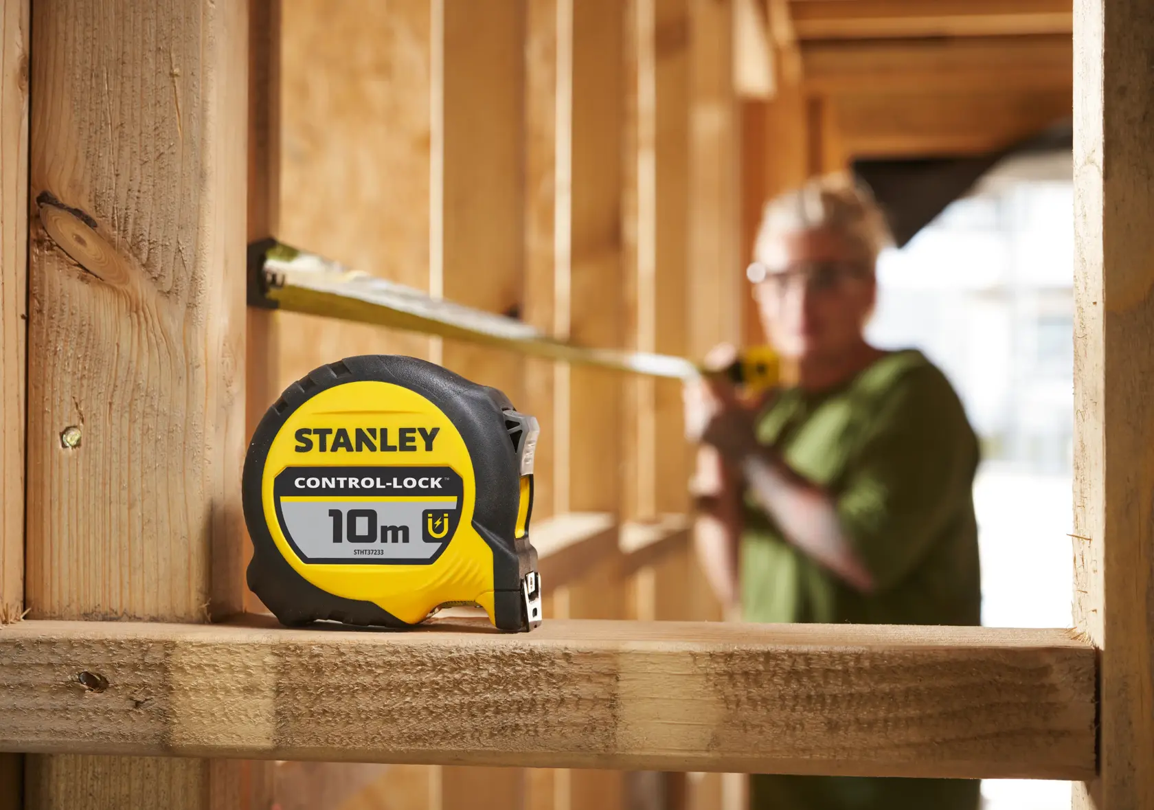 Stanley STHT37233-0 gelbes und schwarzes Maßband, 10m, auf einer Holzkonstruktion gezeigt.