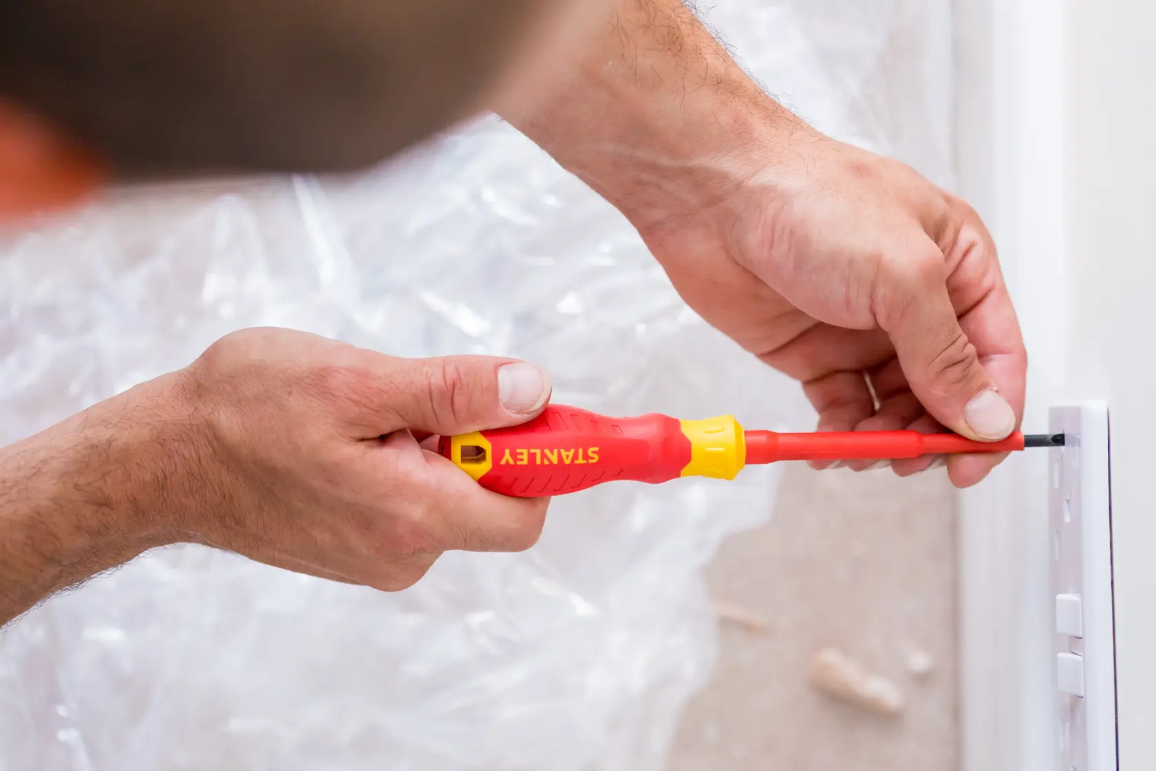 STANLEY STHT60032-0 insulated screwdriver used for electrical work near a light switch.