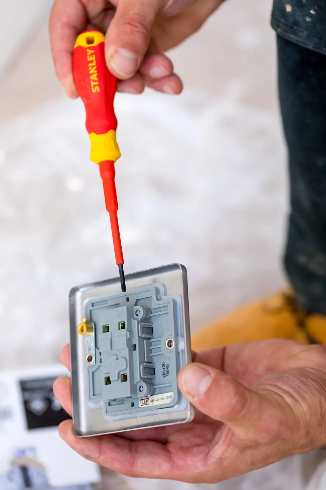 Photo of STANLEY STHT60032-0 insulated screwdriver in use on an electrical outlet, close-up view.