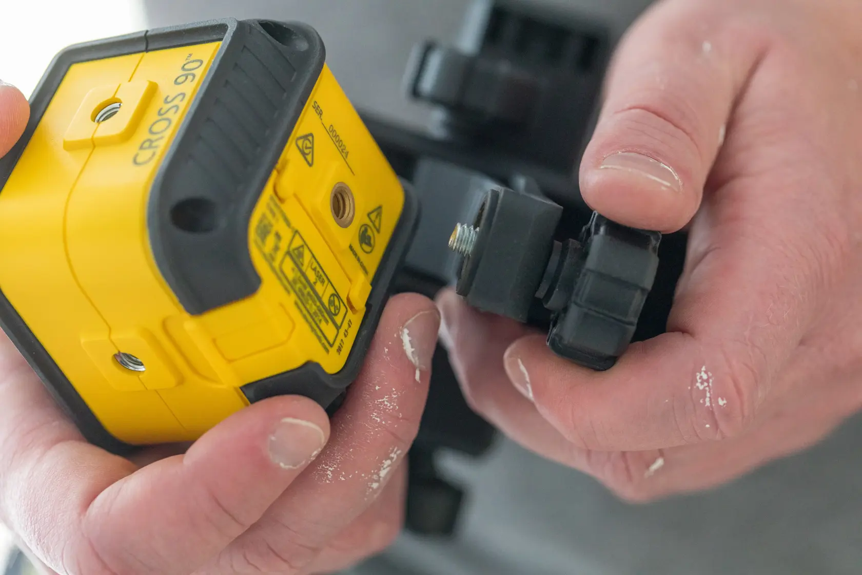 Photo of STANLEY STHT77502-1 laser level being adjusted by hand, yellow and black casing, close-up view.