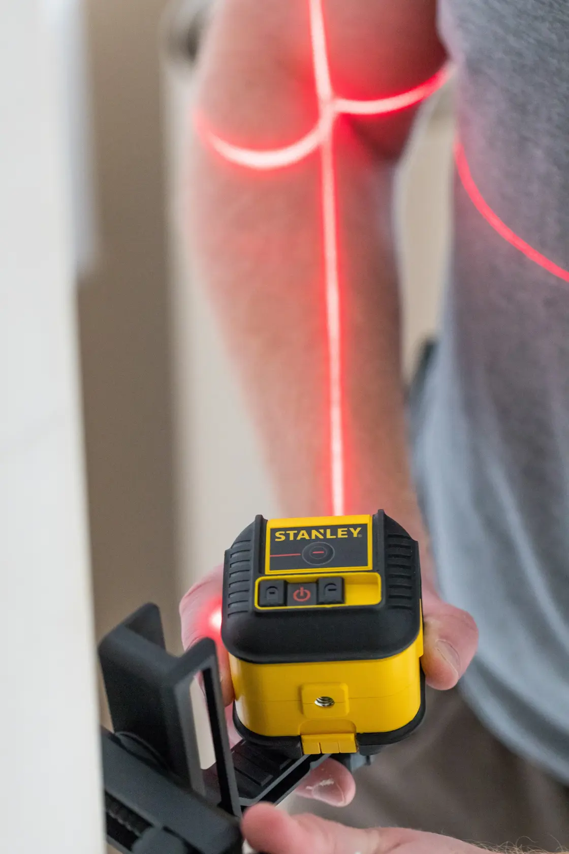 STANLEY STHT77502-1 yellow and black cross line laser level in use projecting red laser lines.