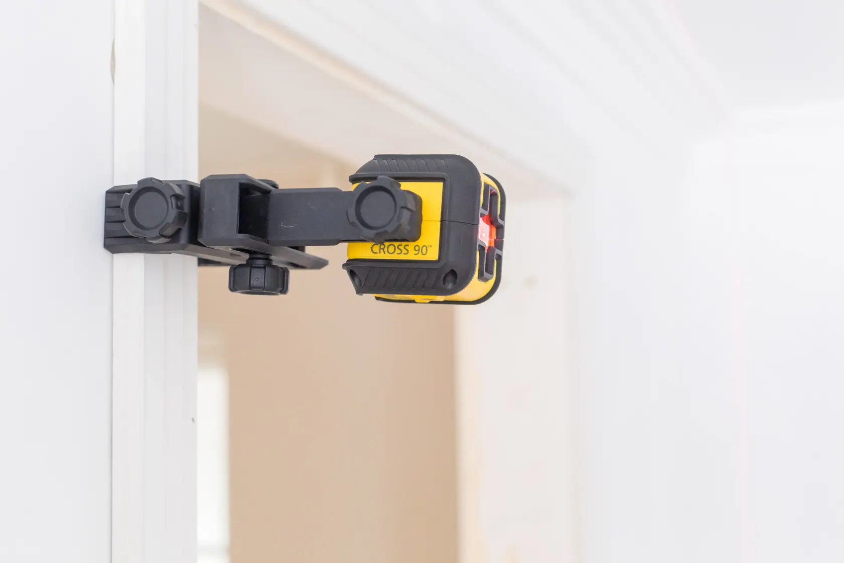 STANLEY STHT77502-1 laser level tool with clamp attached to a door frame, side angle, yellow and black color.