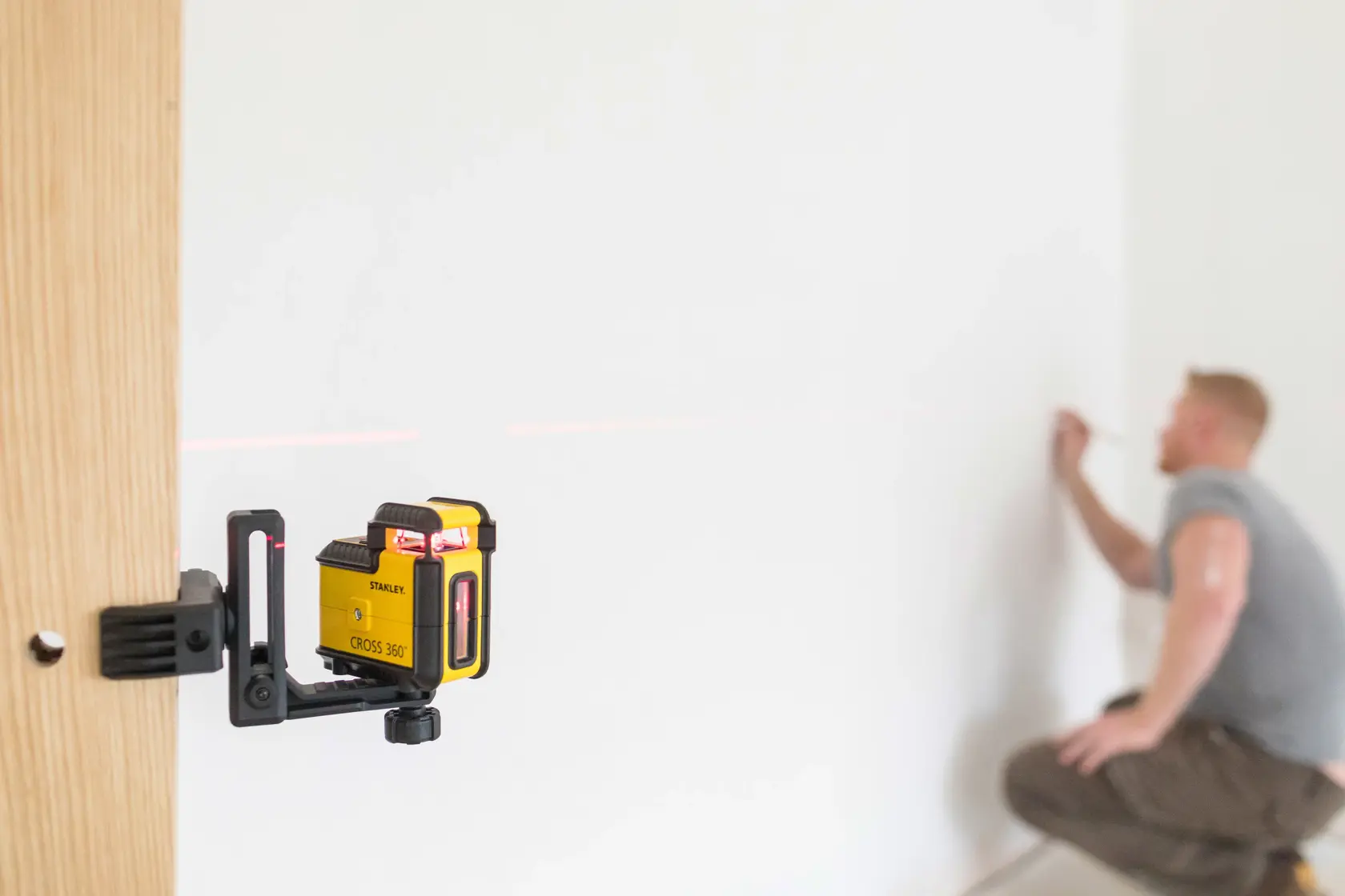 STANLEY STHT77504-1 Laser-Nivelliergerät auf Holz montiert, rote Linie, Person markiert Wand.