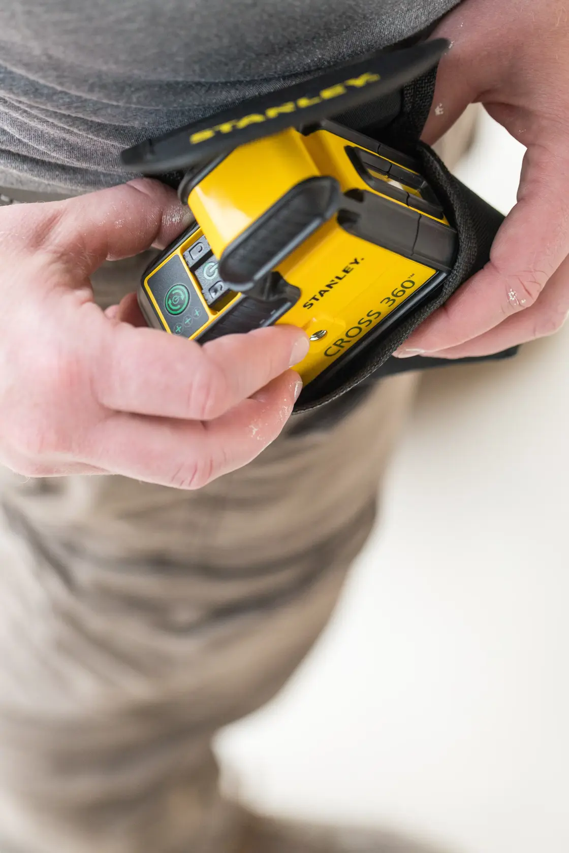 STANLEY STHT77594-1 gelbes Cross 360 Laser-Nivelliergerät in der Hand mit Schutzhülle.