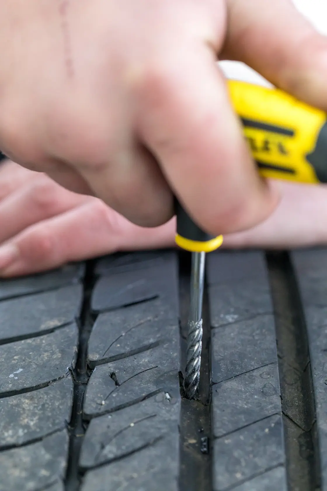 STANLEY STHT80891-0 tire repair tool used on a vehicle tire tread, close-up photography.