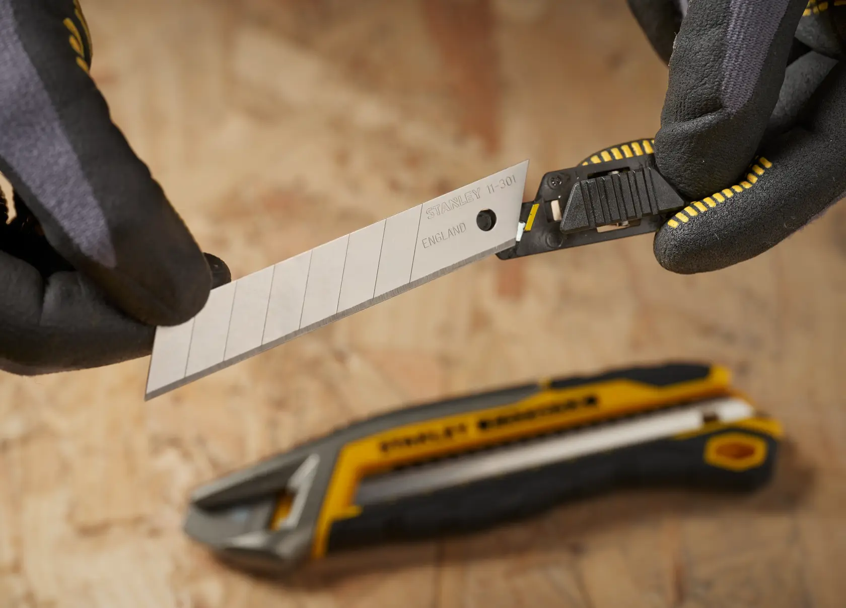 Photo of STANLEY STHT9-11301 snap-off utility knife blade being inserted, close-up with gloves.