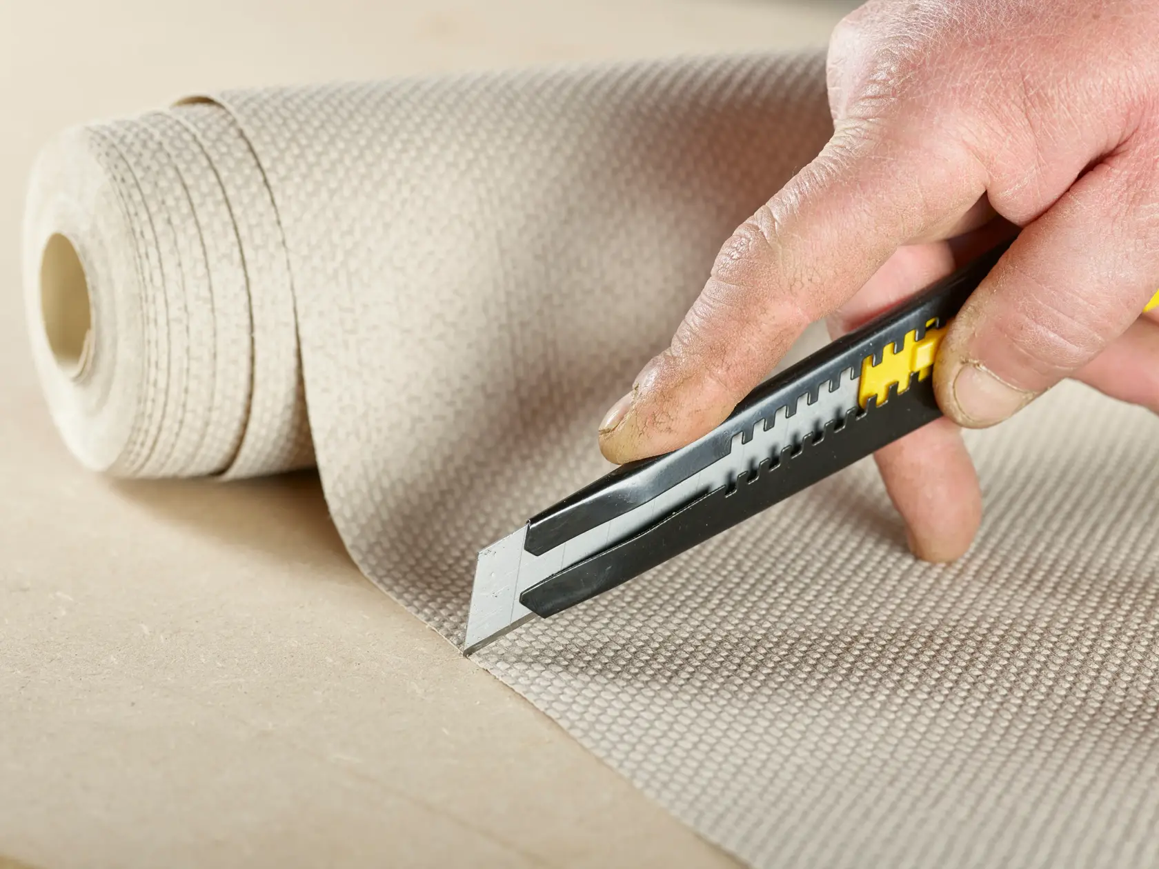 STANLEY STHT9-11301 utility knife cutting textured wallpaper in close-up photography.