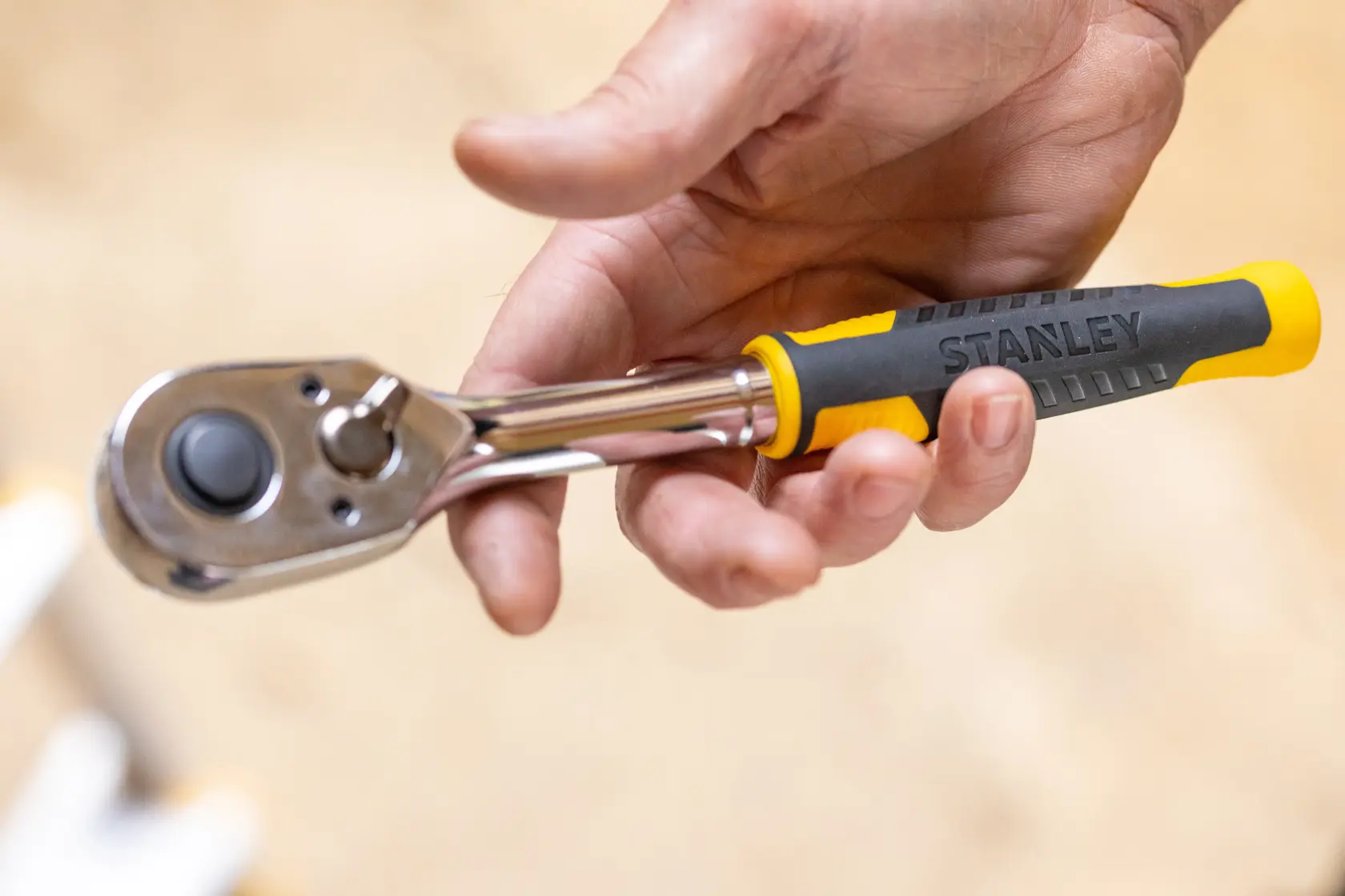 Photo of STANLEY STMT17379-1 ratchet handle with yellow and black grip held in a hand, close-up view.