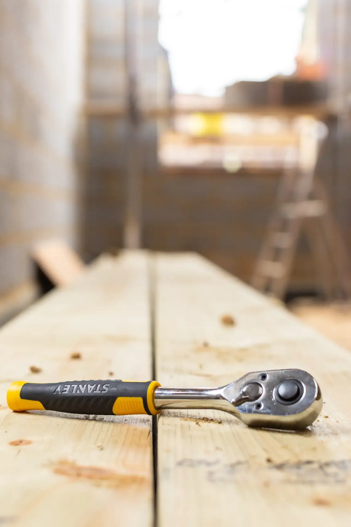 Photo of STANLEY STMT82664-0 ratchet wrench with black and yellow handle on wooden board.