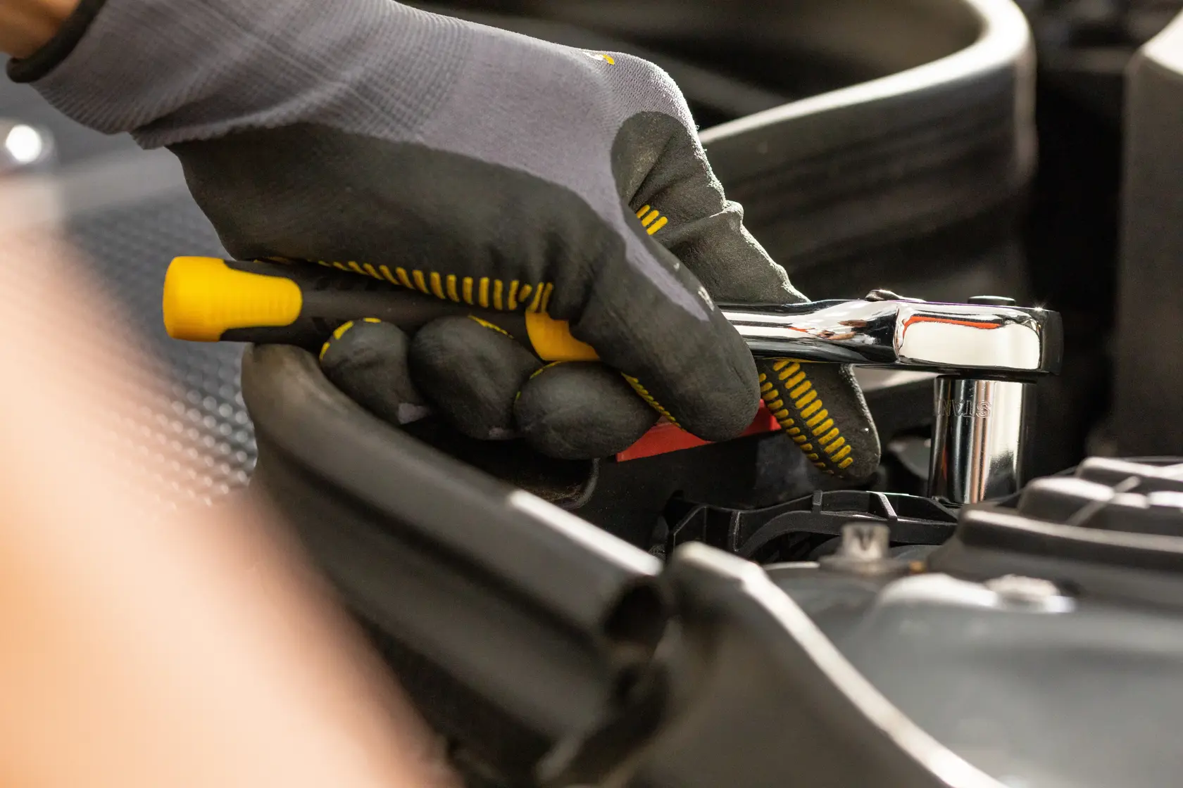 STANLEY STMT82664-0 ratchet wrench in use, close-up photo of hand with glove, automotive context.