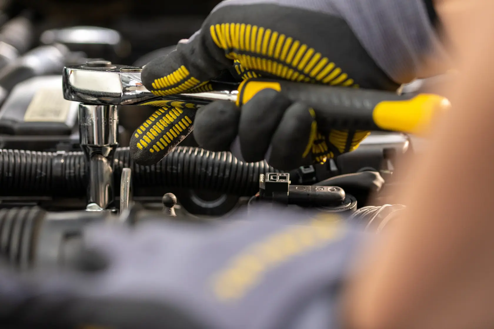 STANLEY STMT82665-0 Ratschen-Schlüssel von einer behandschuhten Hand am Automotor genutzt, Nahaufnahme.