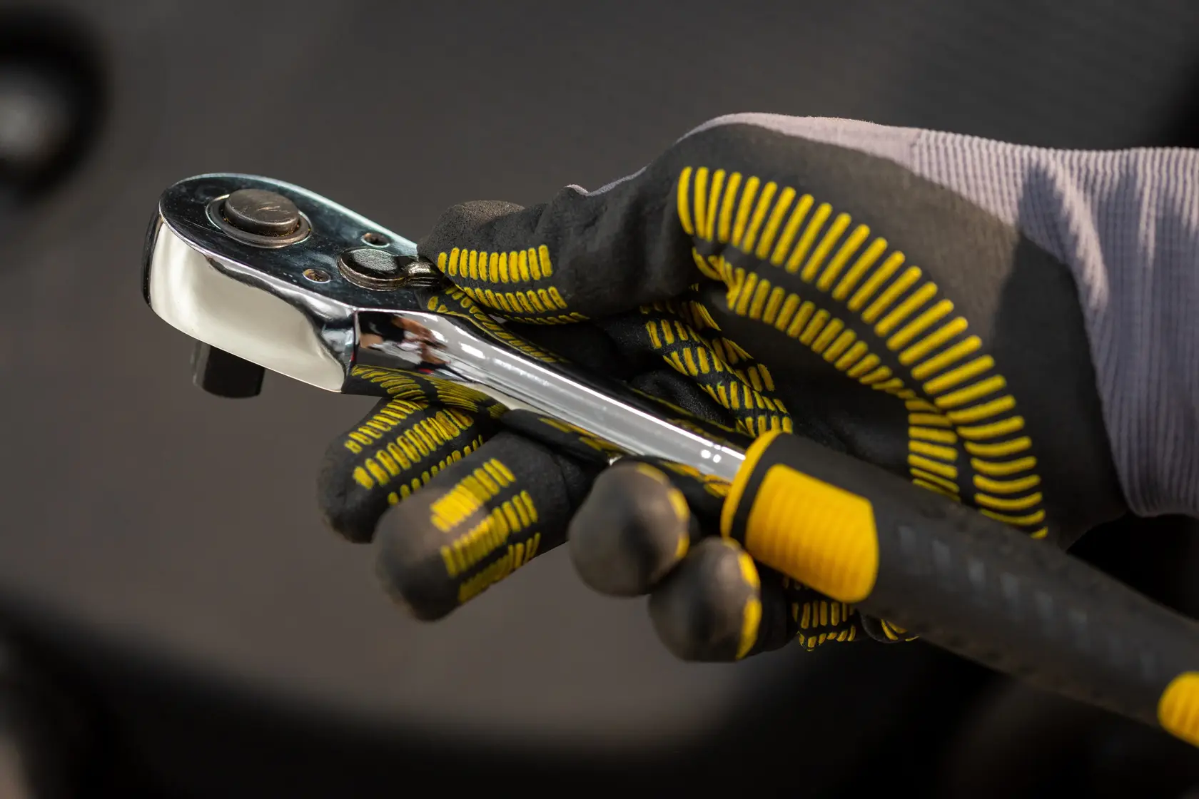 STANLEY STMT82830-1 ratchet wrench held in gloved hand, chrome finish with black and yellow grip.
