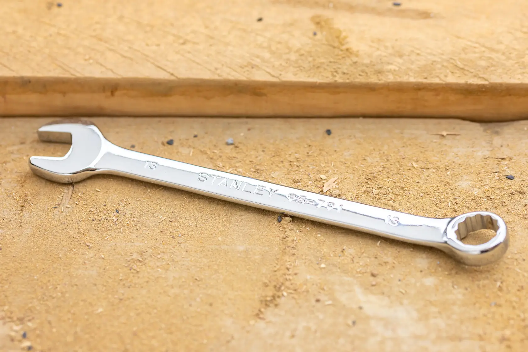 STANLEY STMT82842-0 combination wrench on wood surface, showing open and box ends with chrome finish.