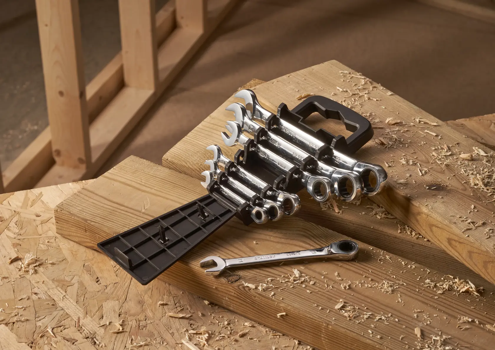 STANLEY STMT82846-0 flat ratcheting wrench set, 7 pieces, on wooden workbench, angled view.